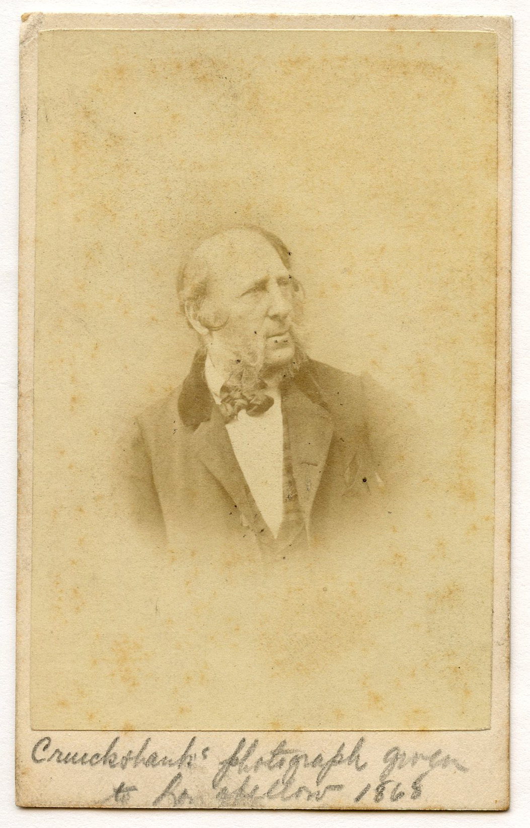 Portrait of a white main. Three-quarter view to subject's left. Balding man with heavy sideburns and whiskers (no hair above or below lips); open coat with velvet lapels and with checked waistcoat visible over a white shirt and dark-colored bow-tie. Head and shoulders silhouetted against blank background.