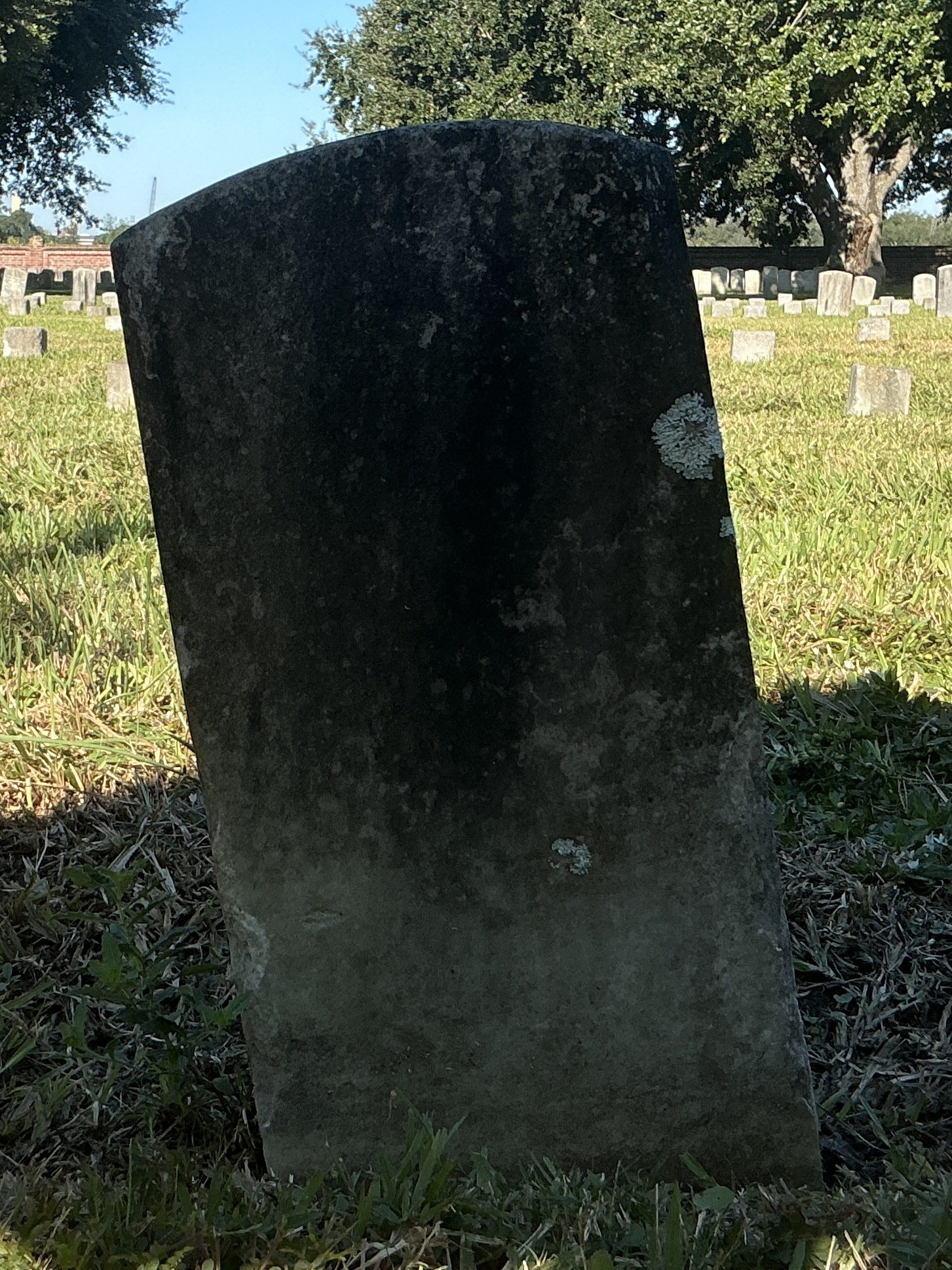 Back of historic upright marble headstone with recessed shield face.