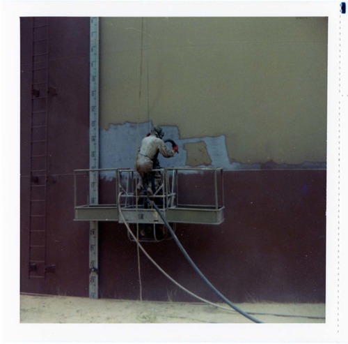 Man repainting the exterior of the million gallon water tank at Birch Creek.