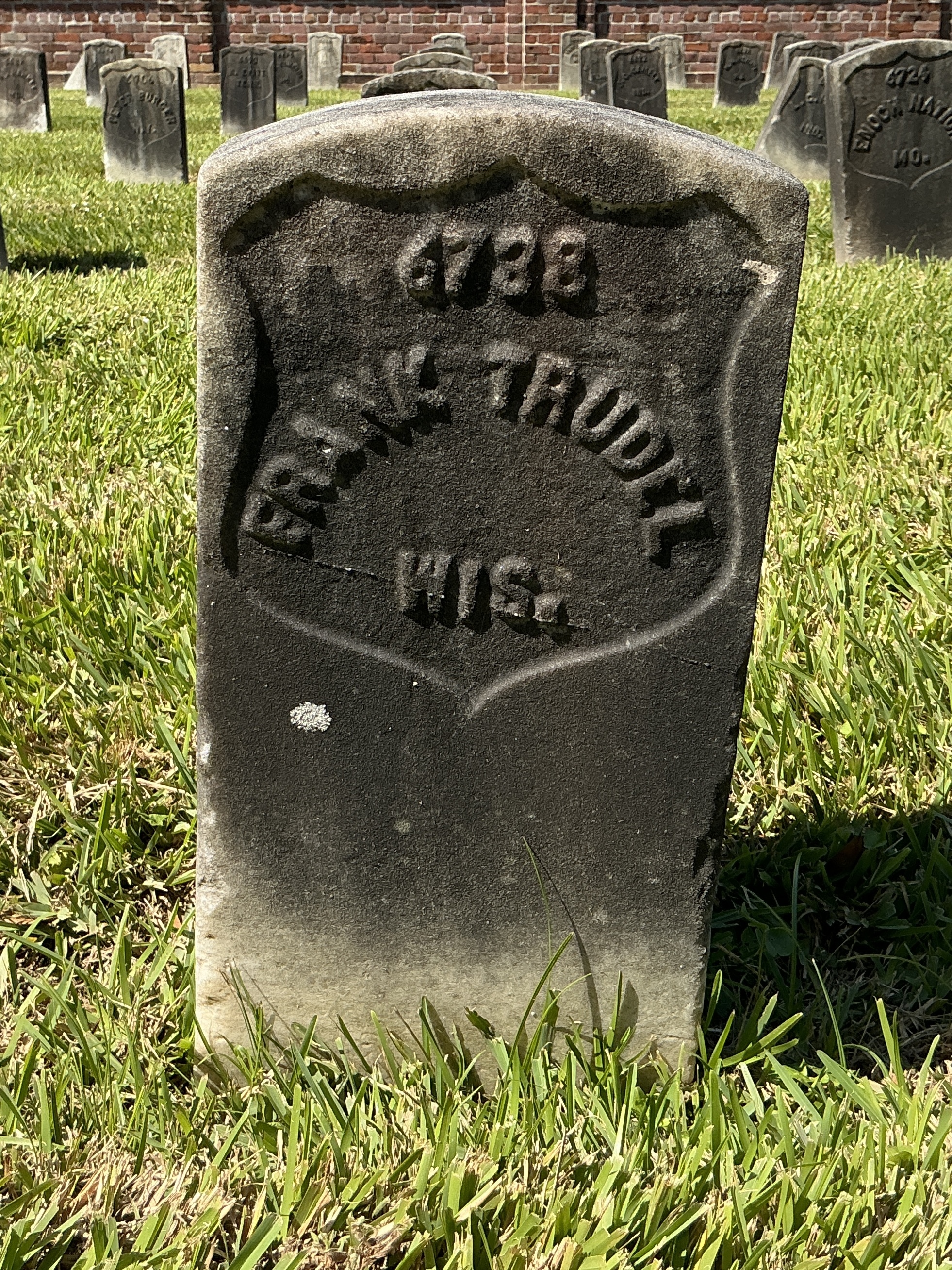 Front of historic upright marble headstone with recessed shield face.