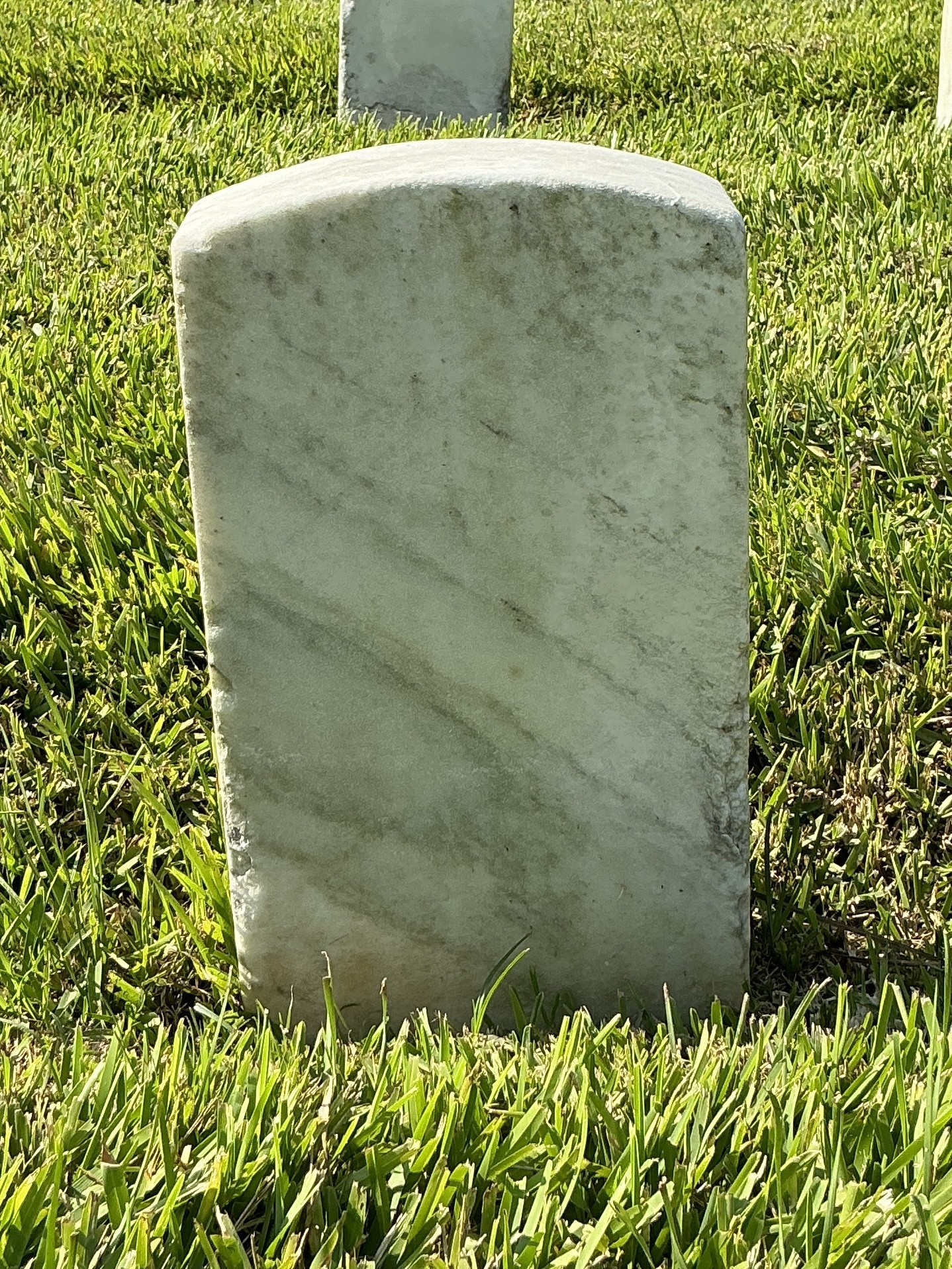 Back of historic upright marble headstone with recessed shield face.
