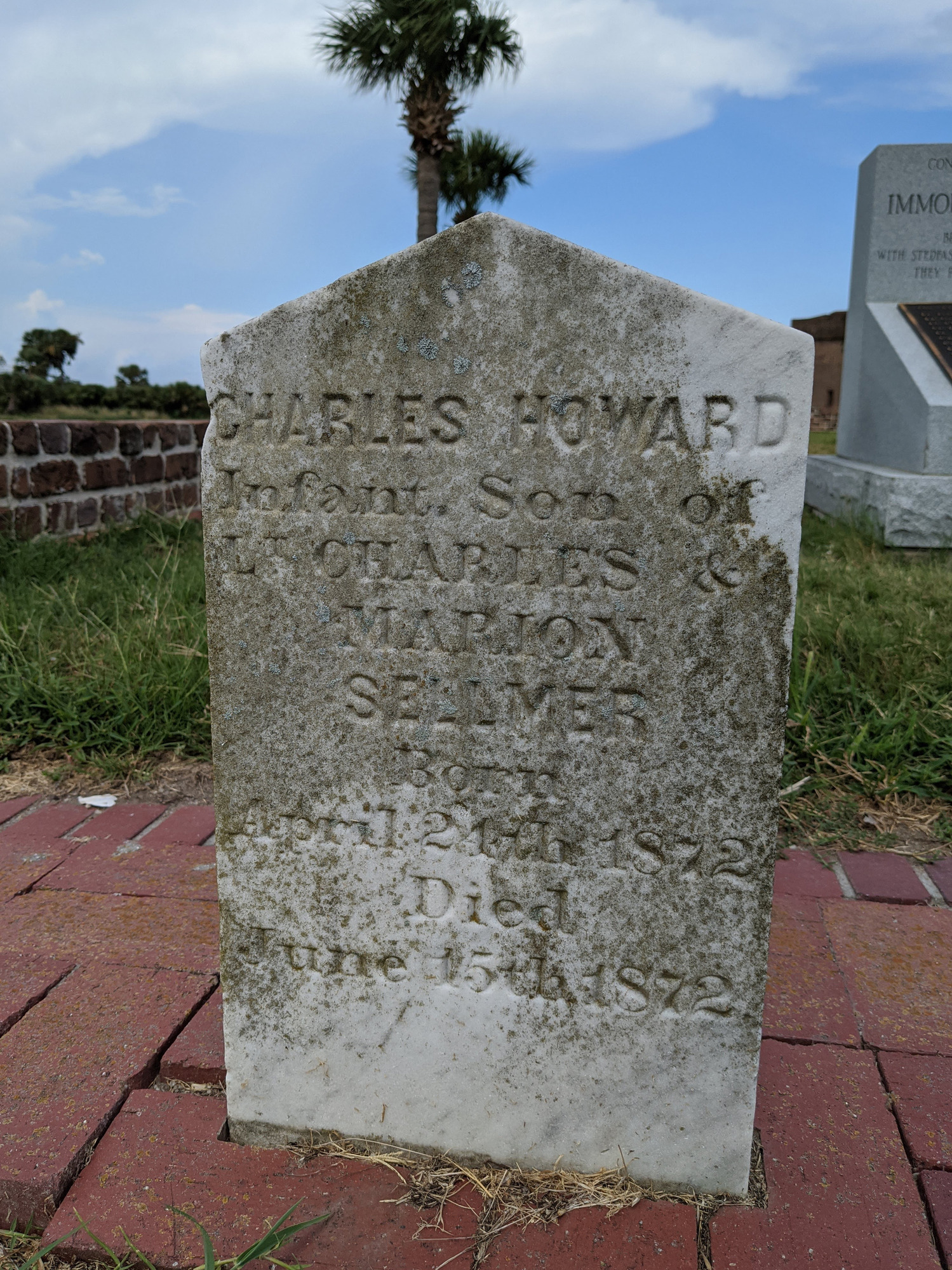 A close-up of a white and grey gravestone which reads “Charles Howard Infant son of Lt. [Lieutenant] Charles & Marion Sellmer Born April 24th 1872 Died June 15th 1872.”
