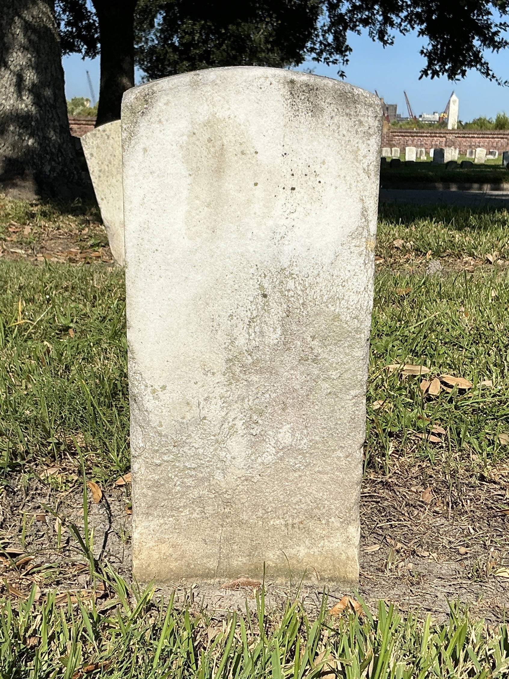 Back of historic upright marble headstone with recessed shield face.