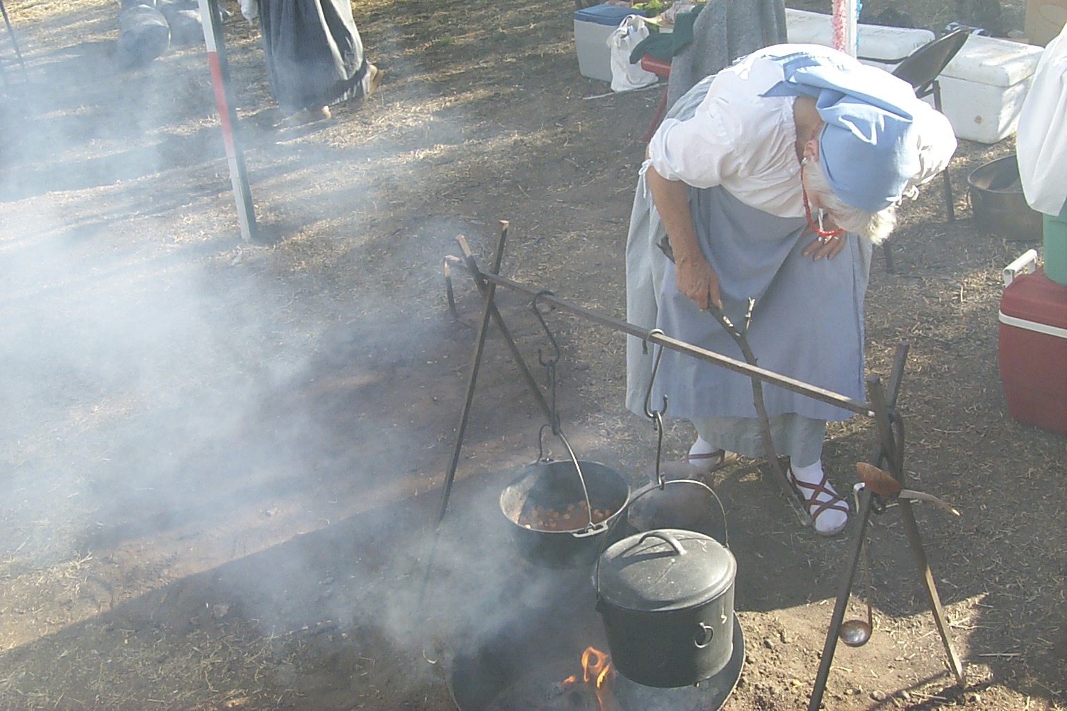 Woman in living history dress cooking over an open fire