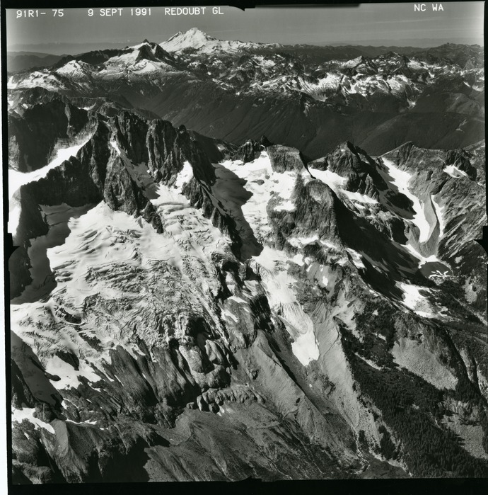 Black and white aerial photograph of glaciated mountain peaks and valleys.