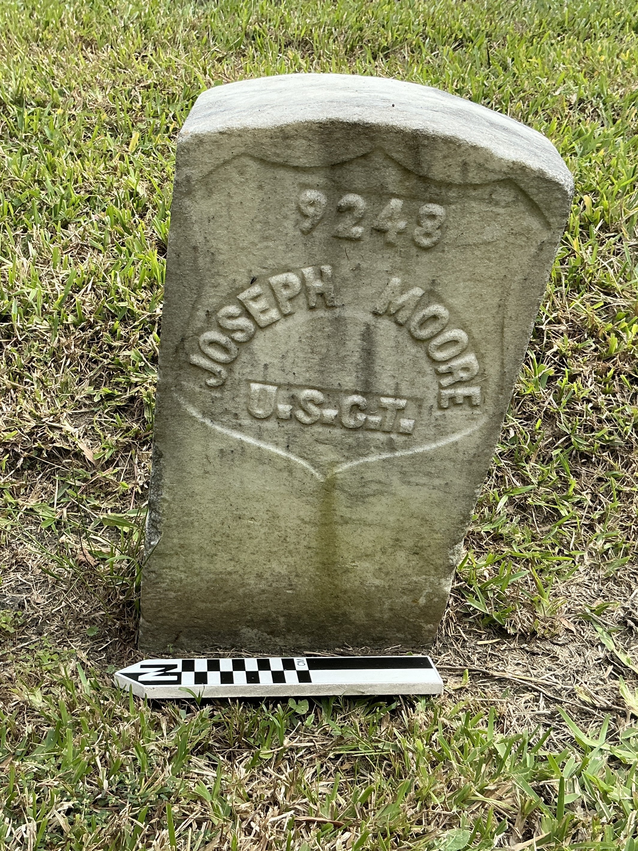 Front of historic upright marble headstone with recessed shield with recessed lettering face.