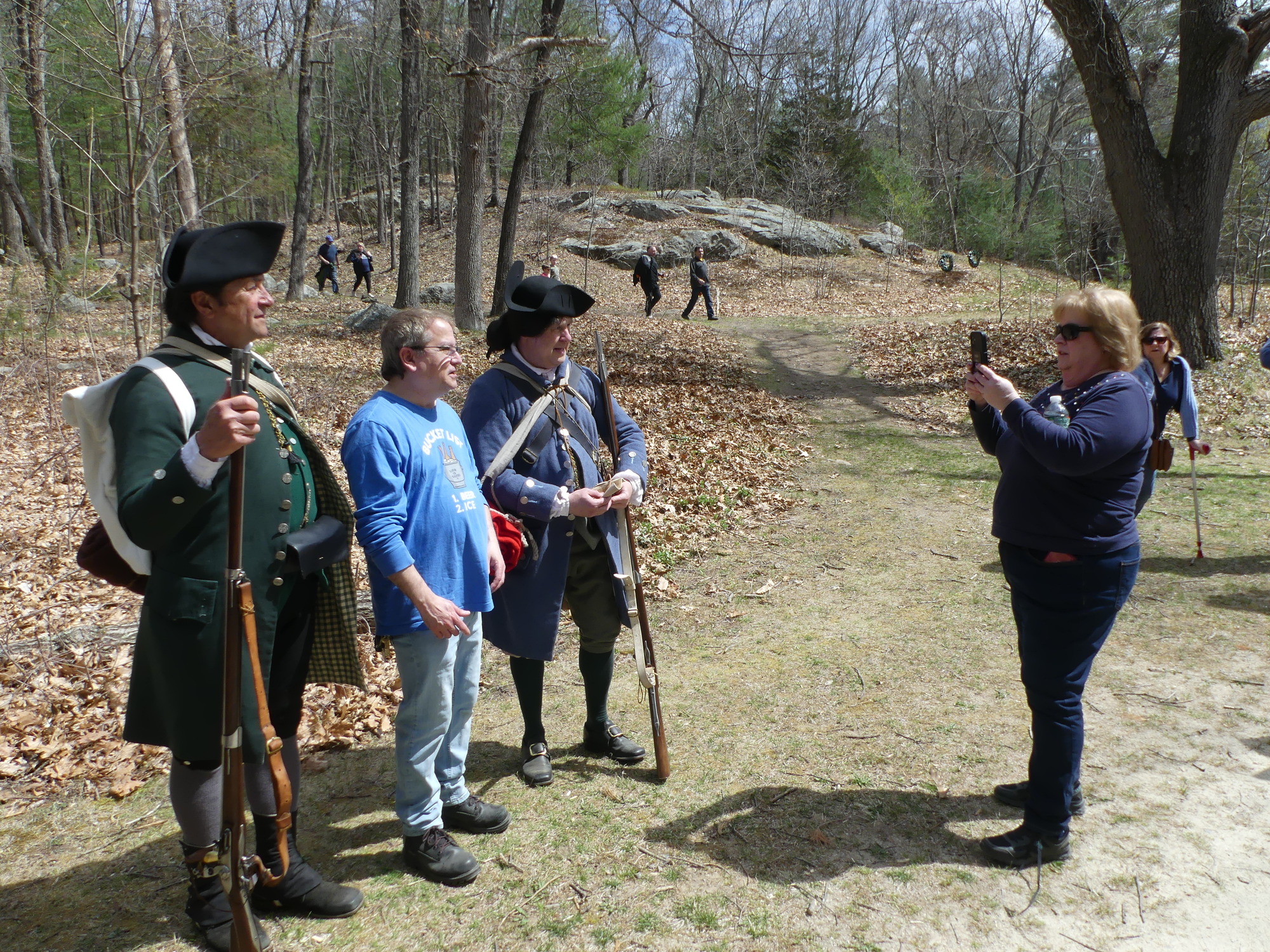 Park visitors taking photographs with reenactors dressed as colonial militia. 
