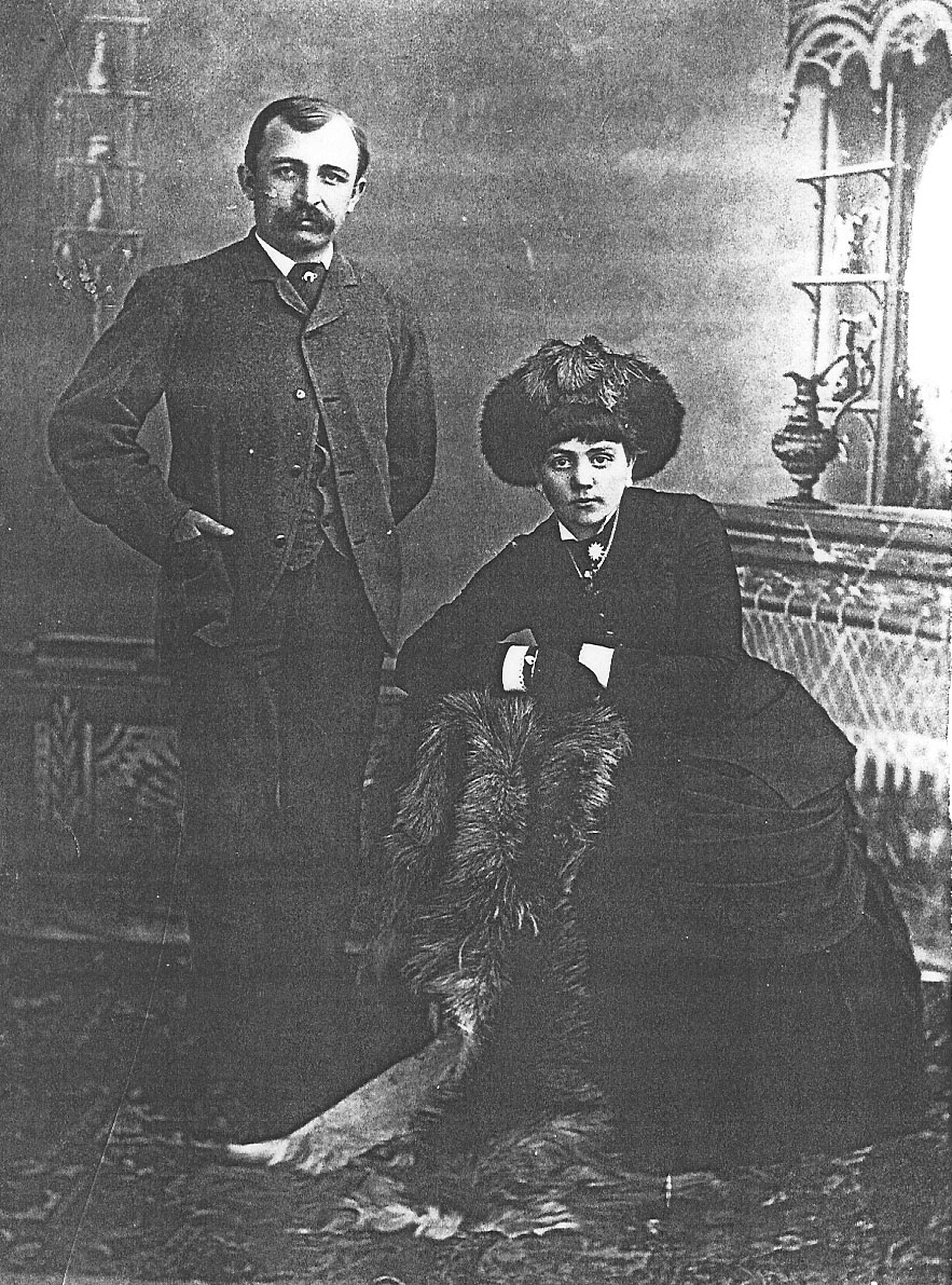Black and white portrait of seated woman and standing man. 