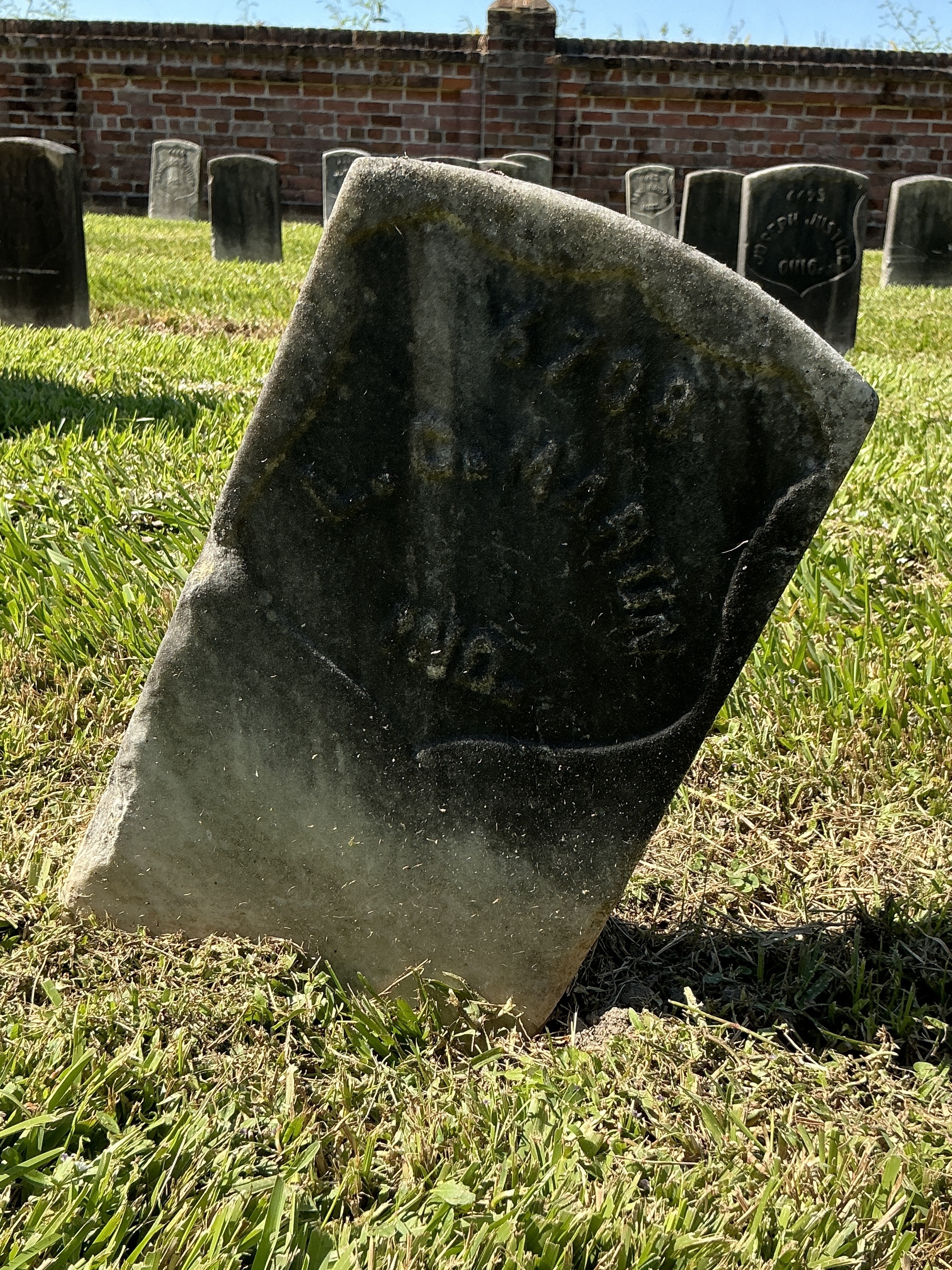 Front of historic upright marble headstone with recessed shield face.
