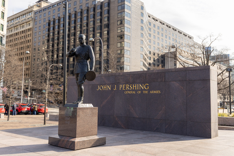 A statue of a man holding his hat in one hand and a pair of binoculars in the other. 