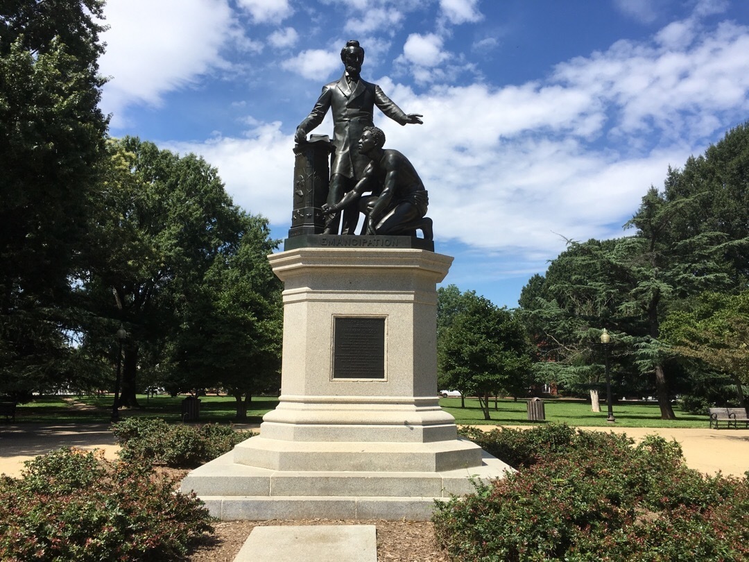 A statue of Abraham Lincoln holding the Emancipation Statue, standing over Archer Alexander, who is kneeling at Lincoln's feet with broken shackles around his wrists. 