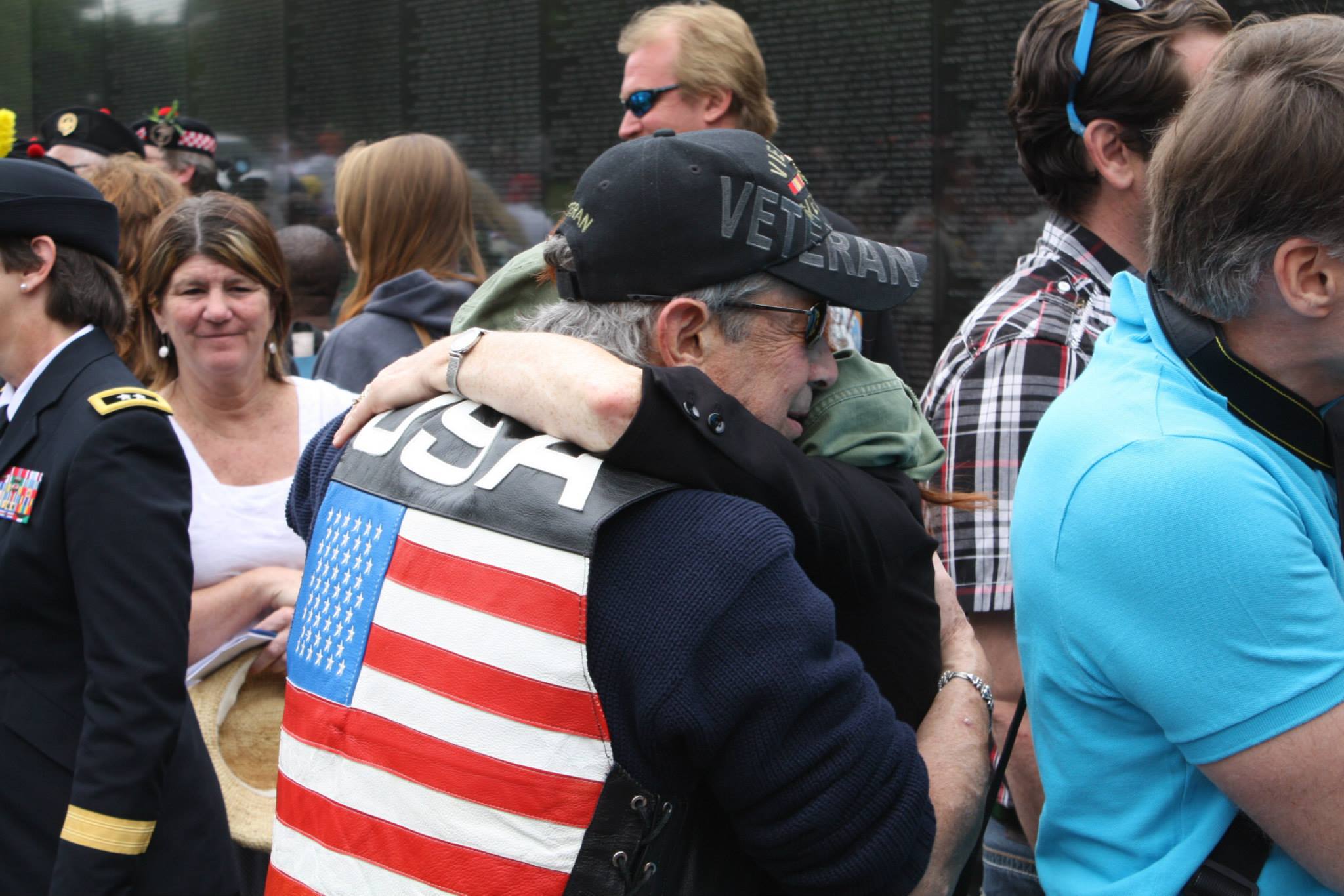A man and woman embrace in front of the Vietnam Wall