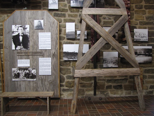 Black and white, historic photos and exhibit text areas are displayed on a wooden panel and the stone wall behind a large, wooden windmill model.