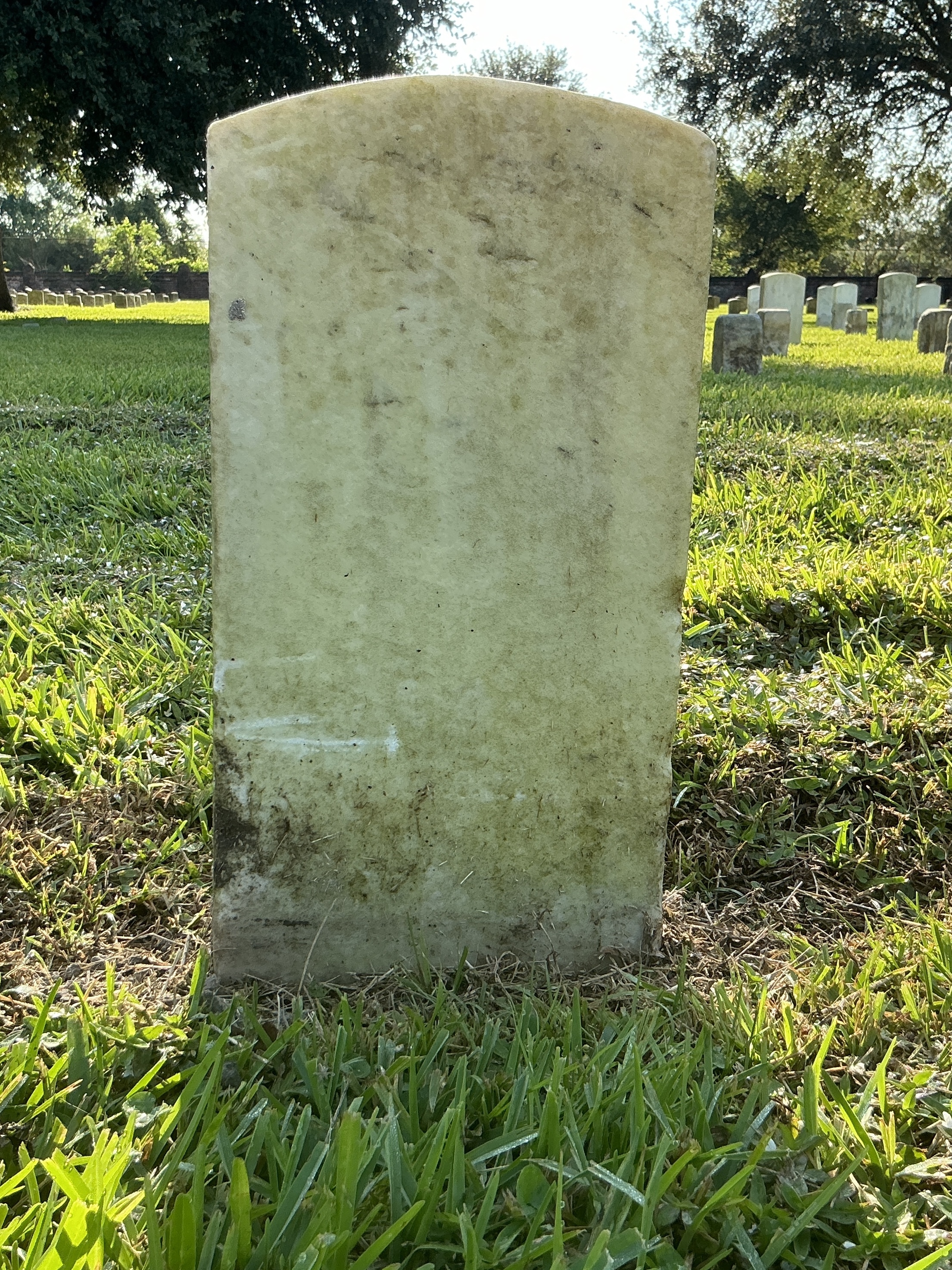 Back of historic upright marble headstone with recessed shield face.