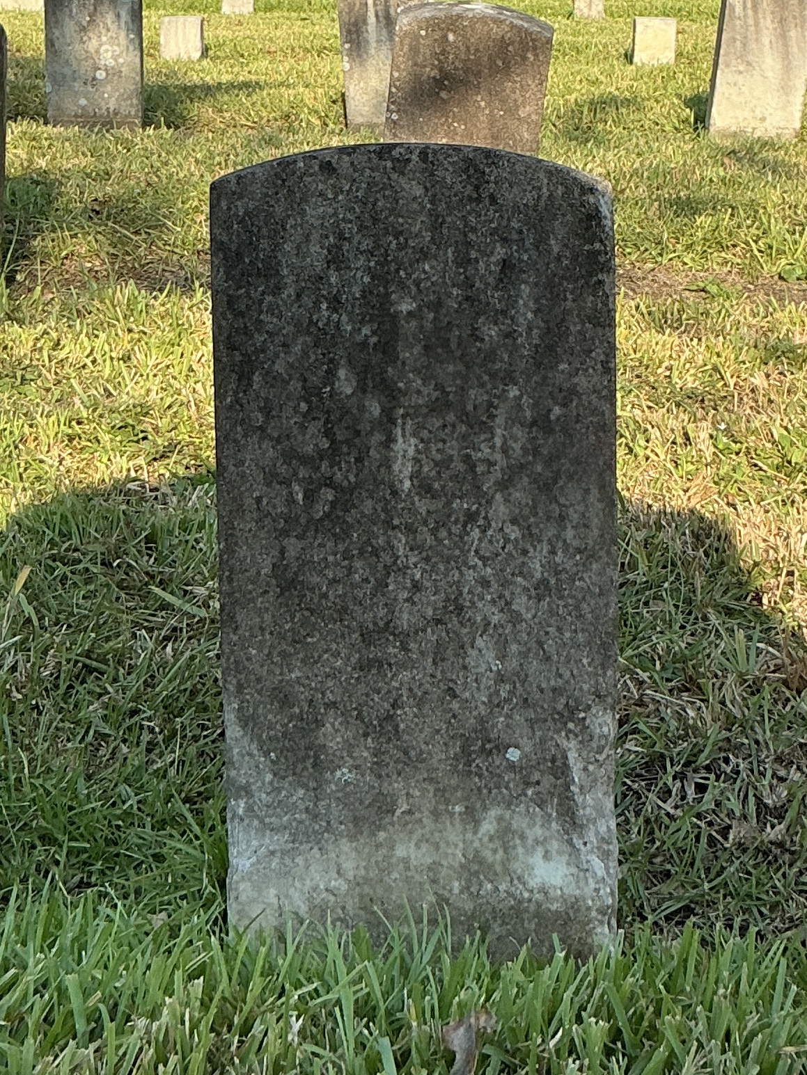 Back of historic upright marble headstone with recessed shield face.
