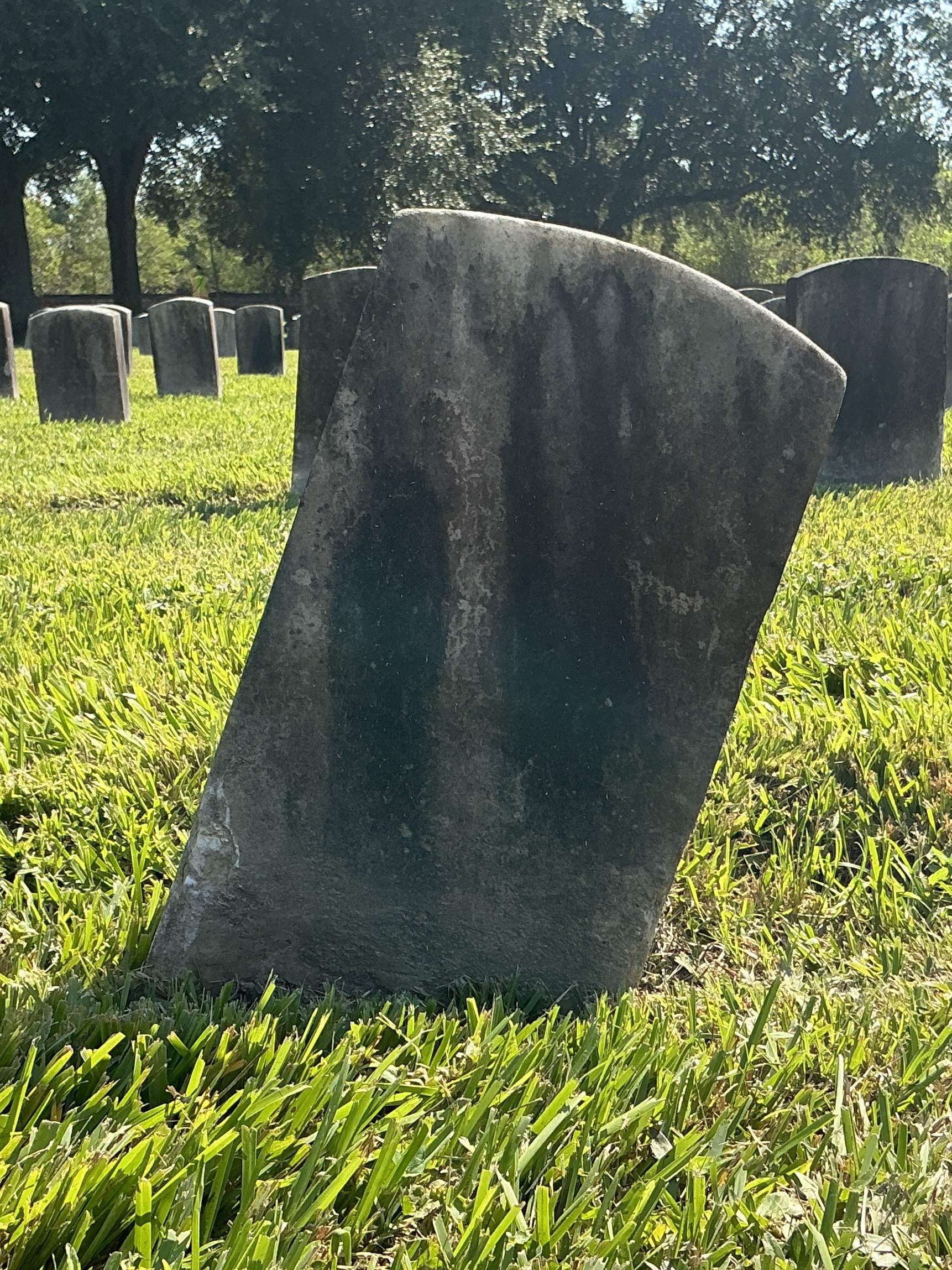 Back of historic upright marble headstone with recessed shield face.