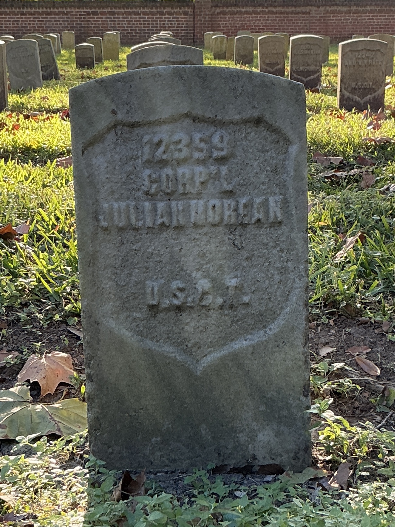Front of historic upright marble headstone with recessed shield face.