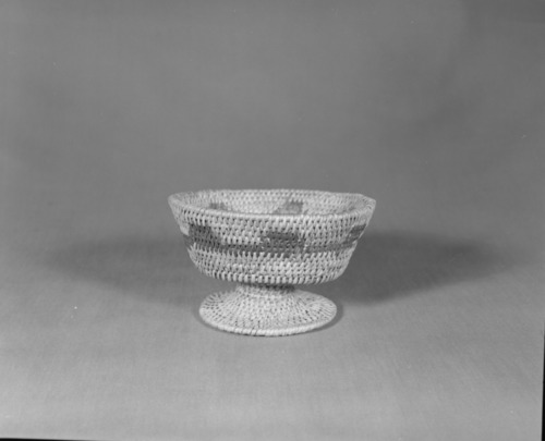 Private Collection. Object: Miwok basket. Dimensions: 5 1/2 x 3 1/4". Materials: Redbud, split shoot that could be bull pine. Technology: Pedestal base was made and attached by two or three stitches. Collection History: Made for the owner when she was a child, by Matilda, a Sonora Miwok, c. 1920. Photographed by Michael Dixon. Catalogued by Craig Bates and Barbara Beroza. Yosemite Collections, National Park Service.