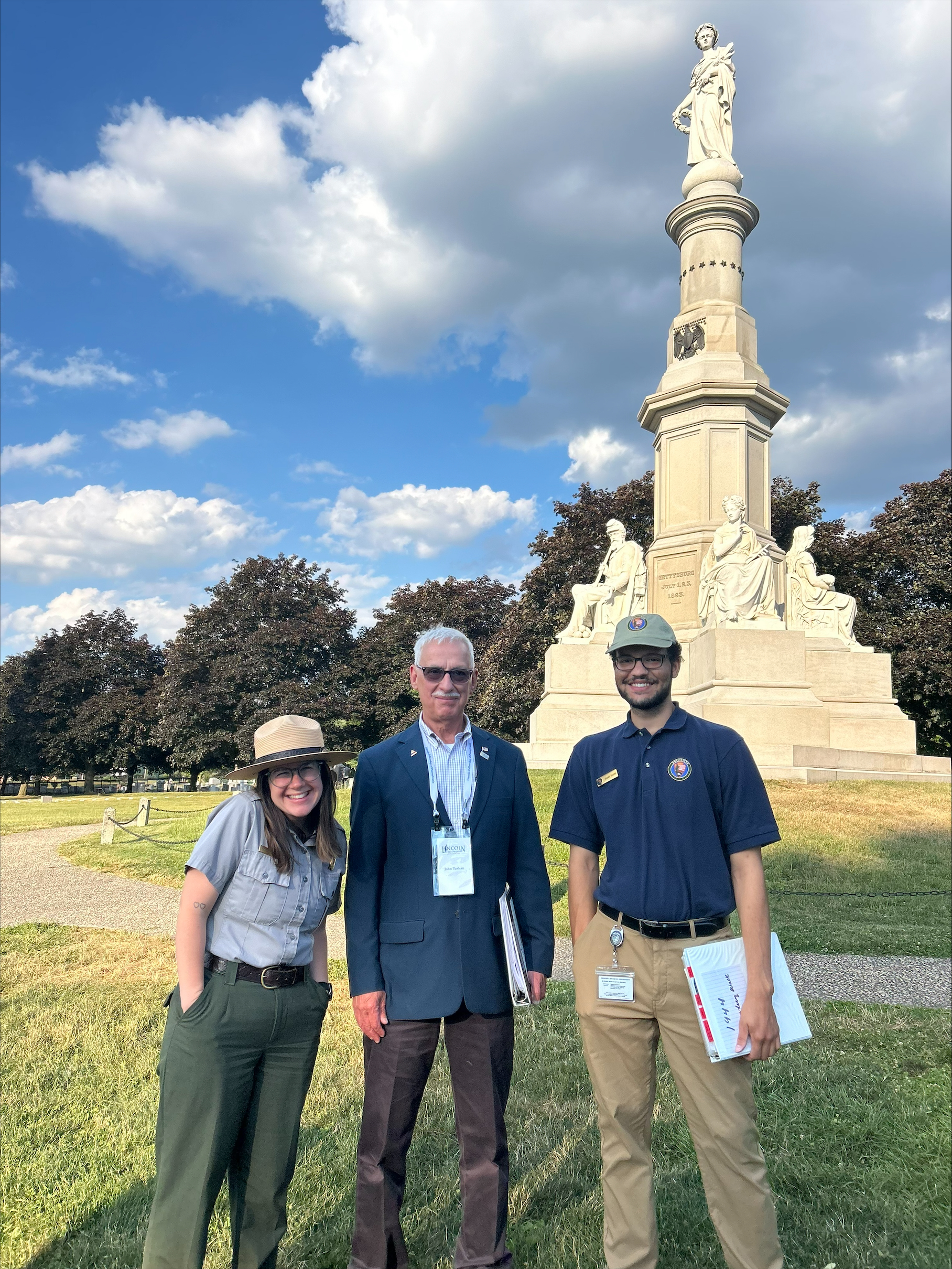 Park intern Alex Rosenthal stands next to Lincoln Fellowship Historian John Tuskan and Eisenhower Park Ranger Eva Bauder at the 100 Nights of Taps program in Gettysburg National Cemetery