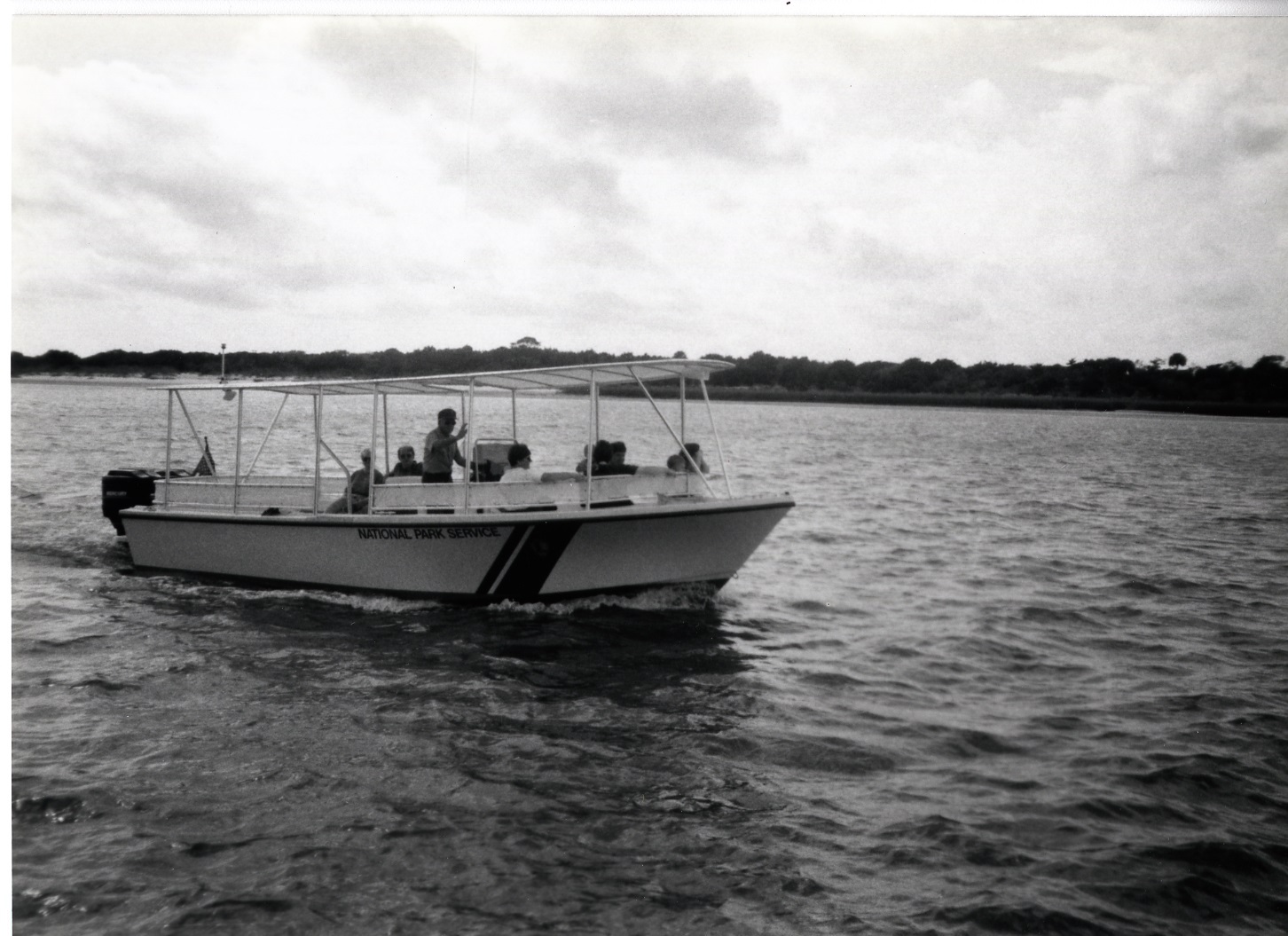 White fiberglass v-hulled boat with canopy.  Stripe on the side and text reading National Park Service