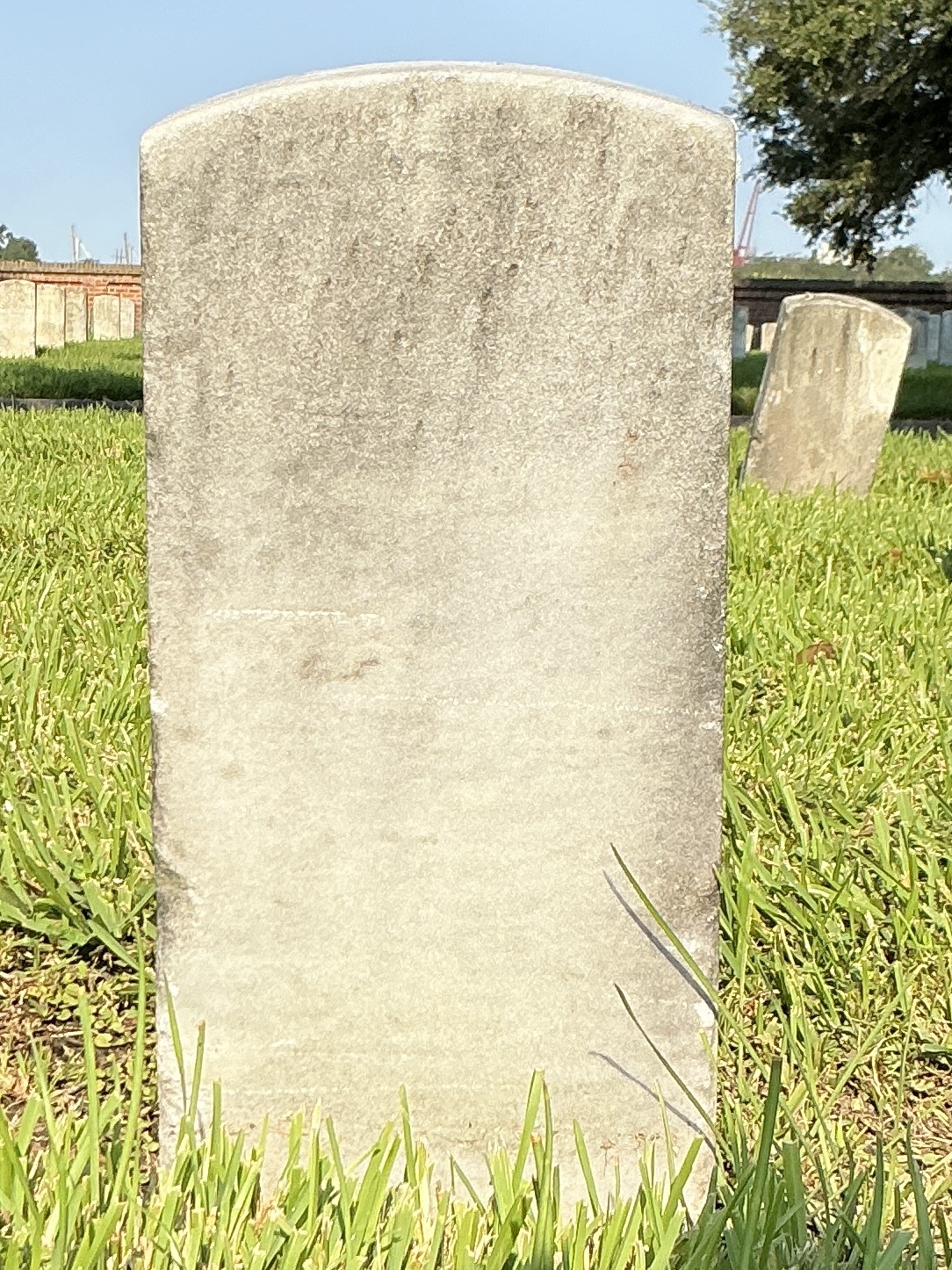 Back of historic upright marble headstone with recessed shield face.