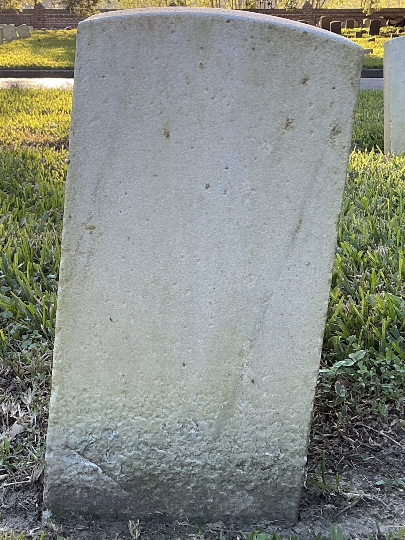 Back of historic upright marble headstone with recessed shield face.