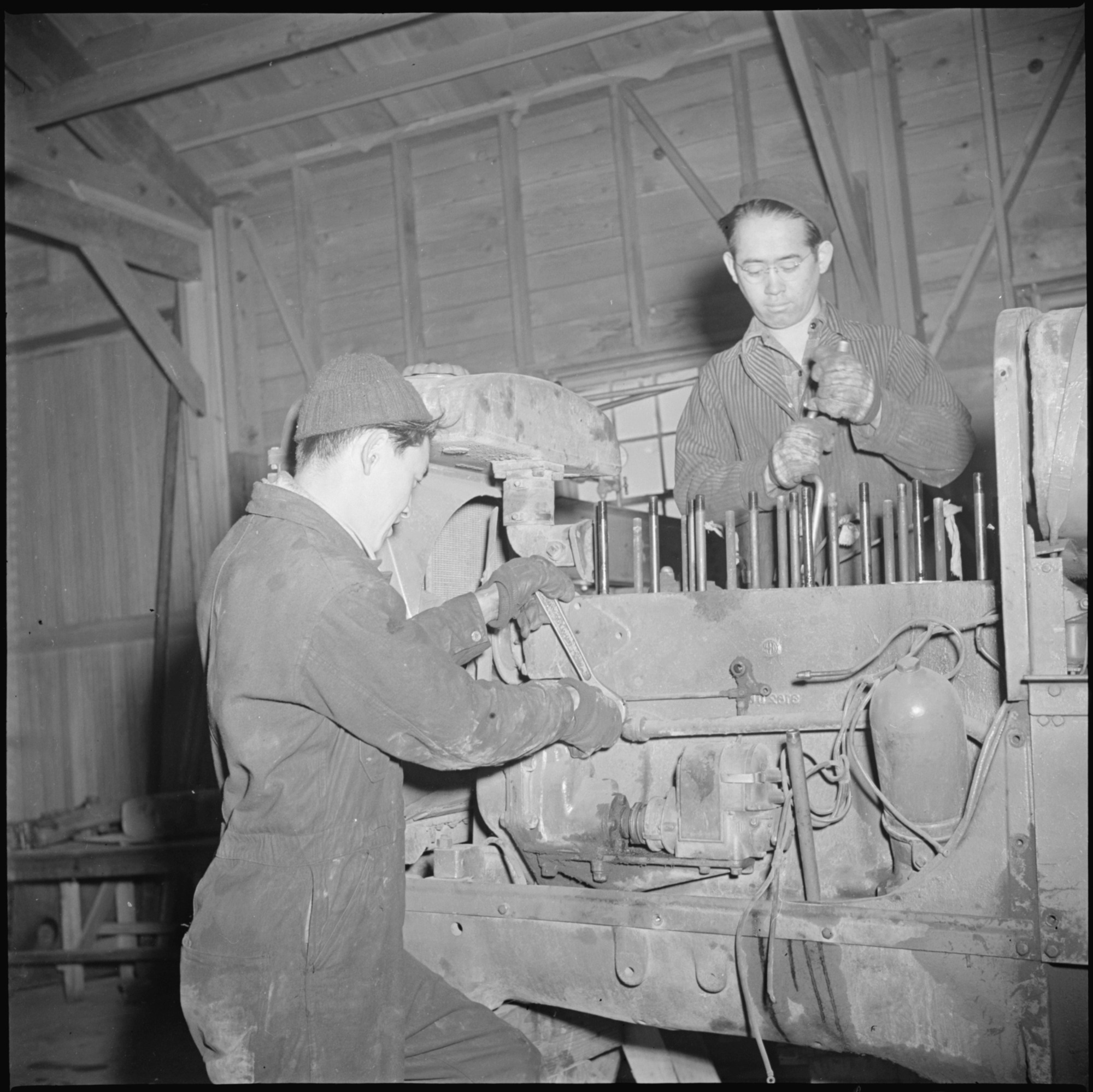 An expert job of motor repairing is done on a heavy truck by garage mechanics. All repair work on cars, trucks, tractors, and other motor vehicles is done by evacuee mechanics