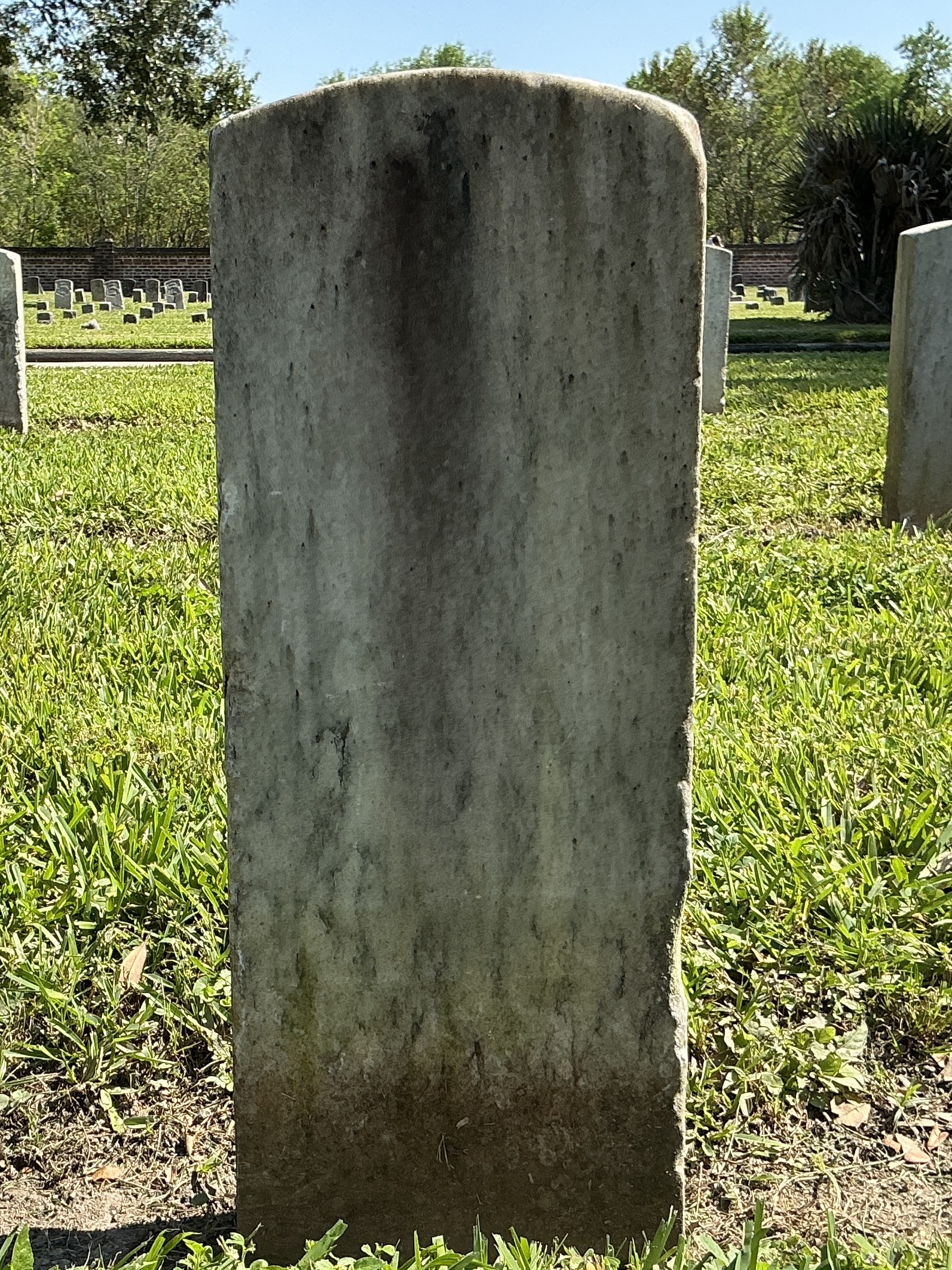 Back of historic upright marble headstone with recessed shield face.