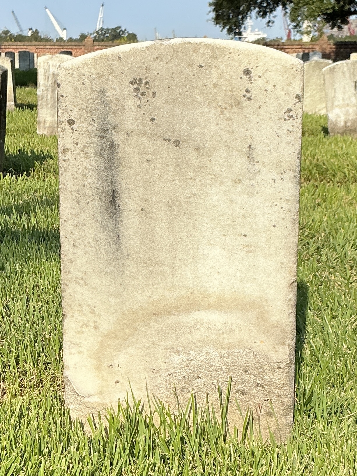 Back of historic upright marble headstone with recessed shield face.