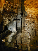 Handrails line the edge of a large vertical cave shaft.