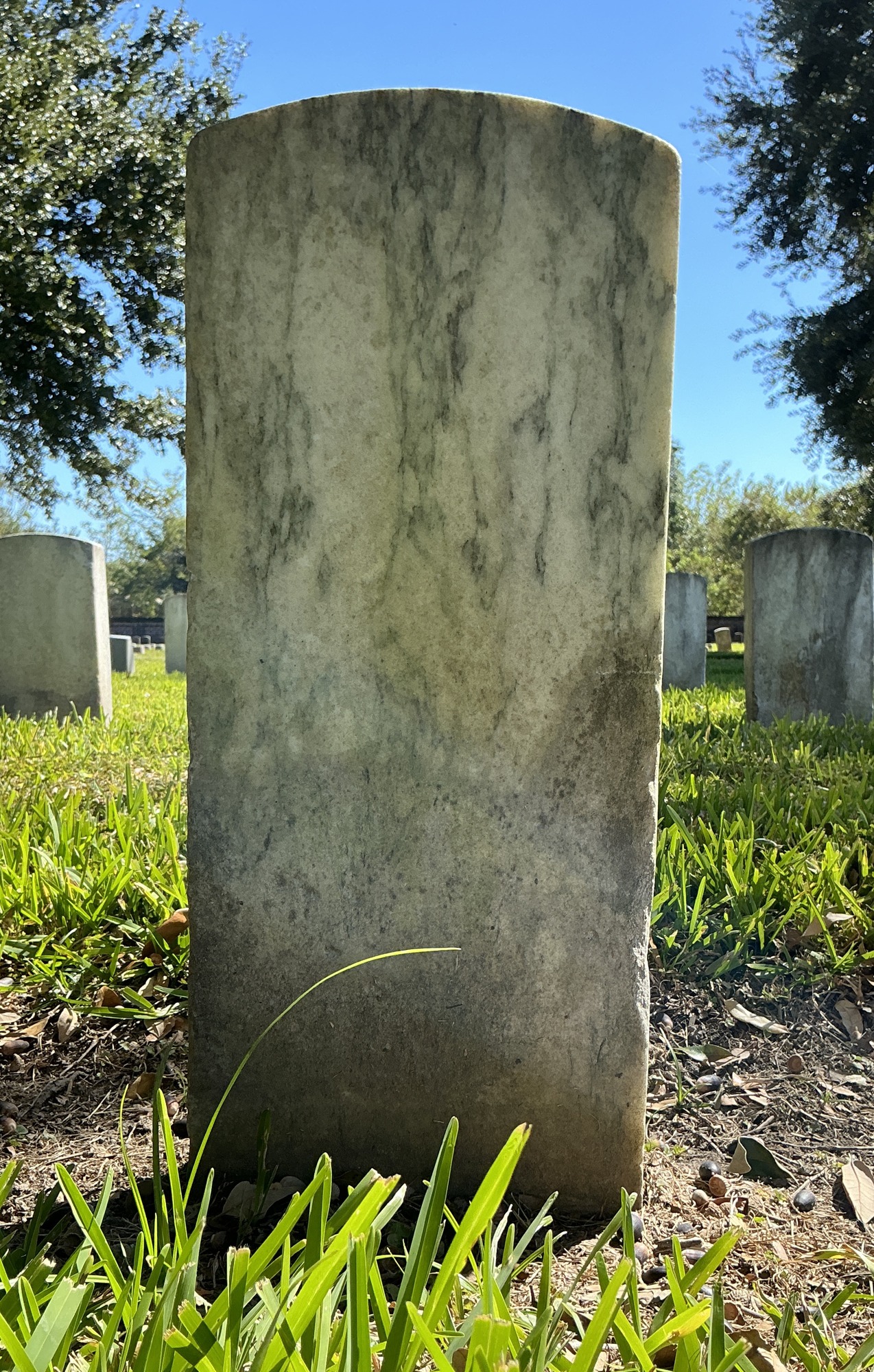 Back of historic upright marble headstone with recessed shield face.