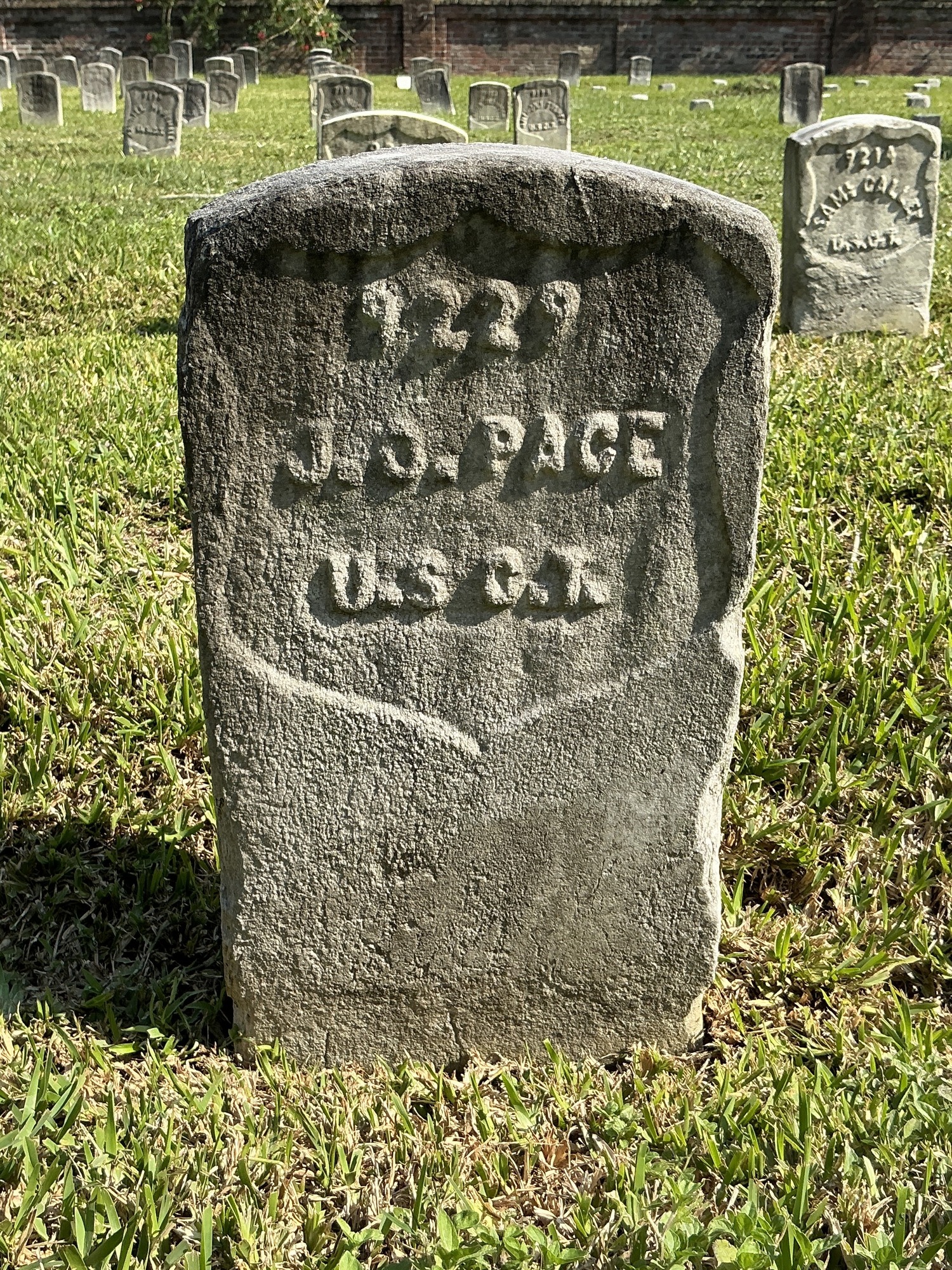 Front of historic upright marble headstone with recessed shield with recessed lettering face.