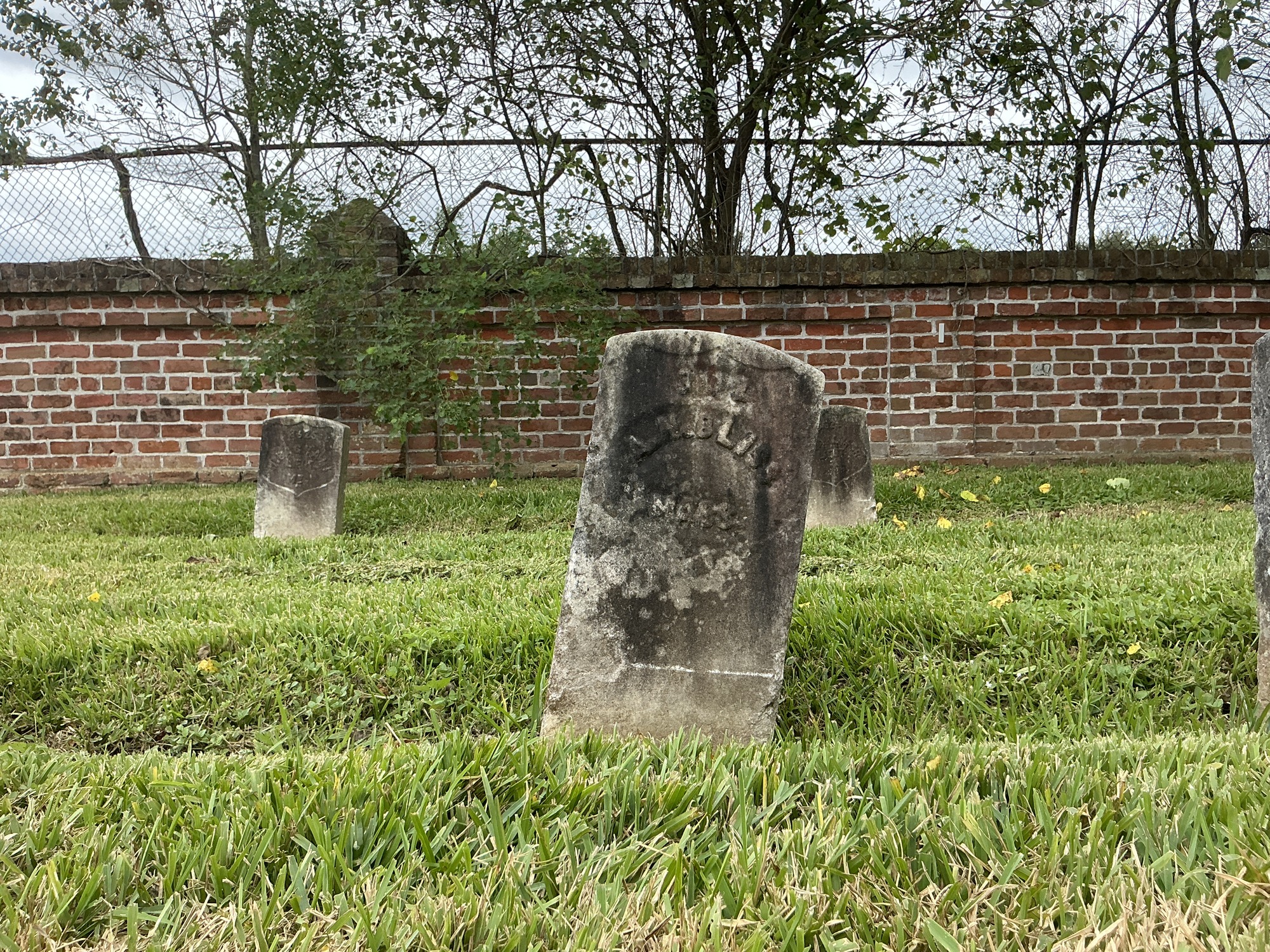 Front of historic upright marble headstone with recessed shield with recessed lettering face.