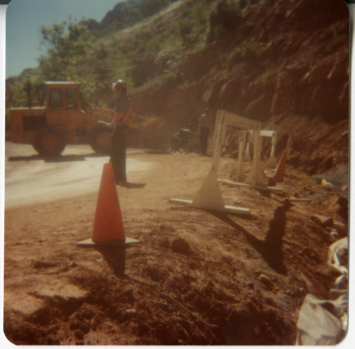 Man monitoring roads with traffic cones and constriction barriers in place behind him.