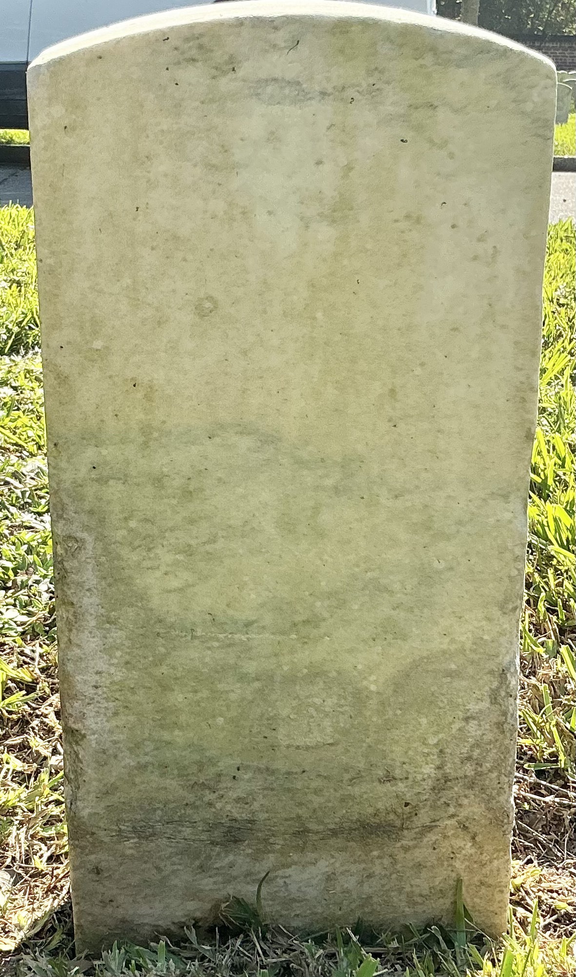 Back of historic upright marble headstone with recessed shield face.