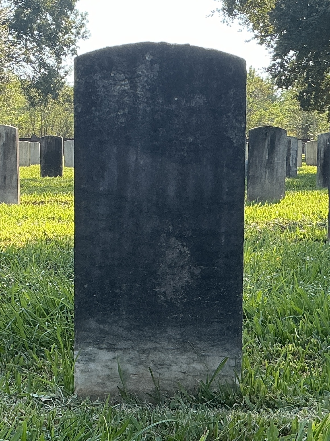 Back of historic upright marble headstone with recessed shield face.
