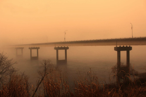 road bridge seen through fog over a river