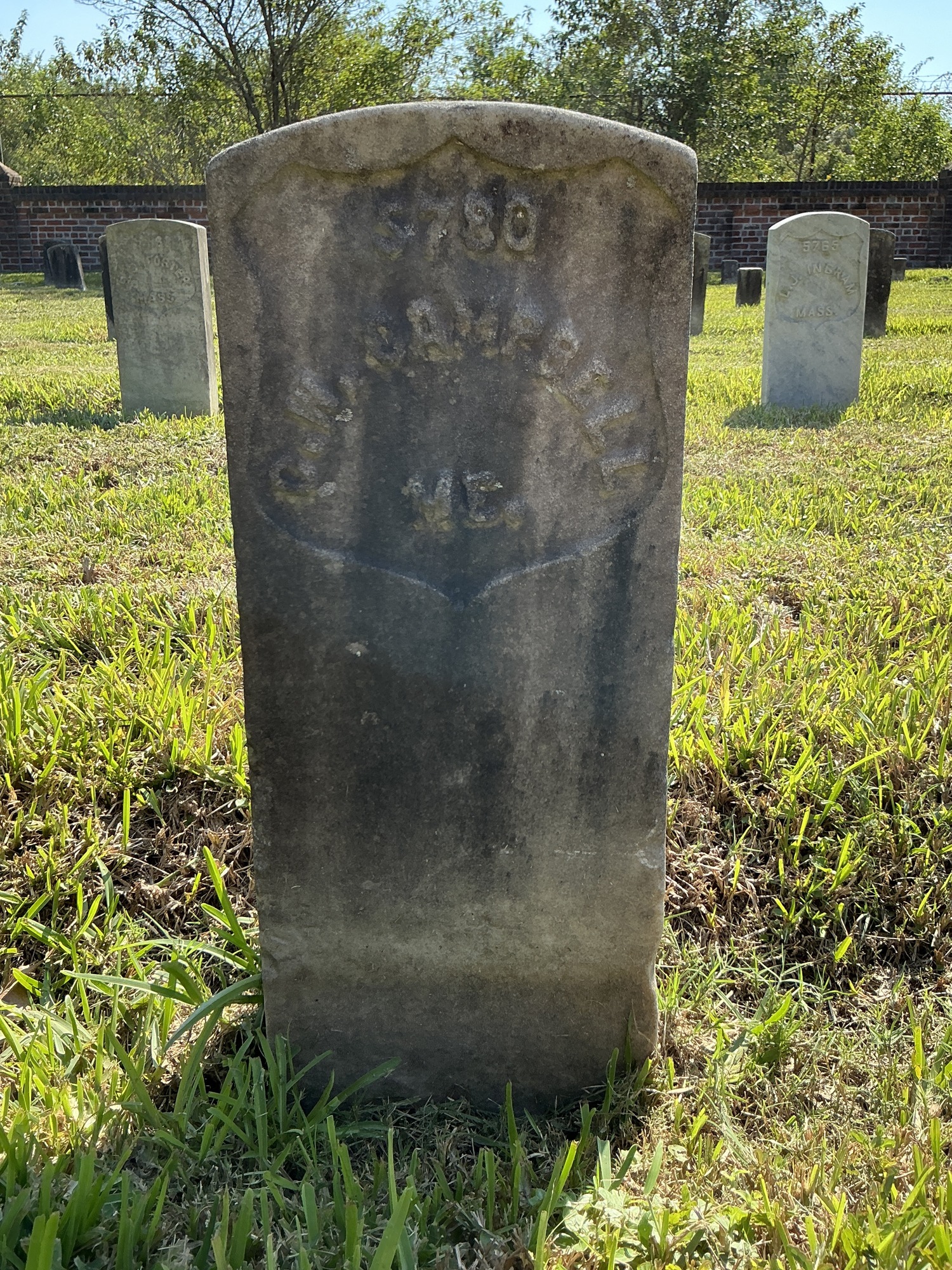 Front of historic upright marble headstone with recessed shield face.