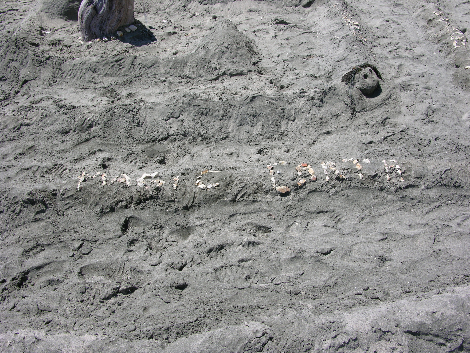 The words magic and Earth written using small rocks on a small ridge made of sand.