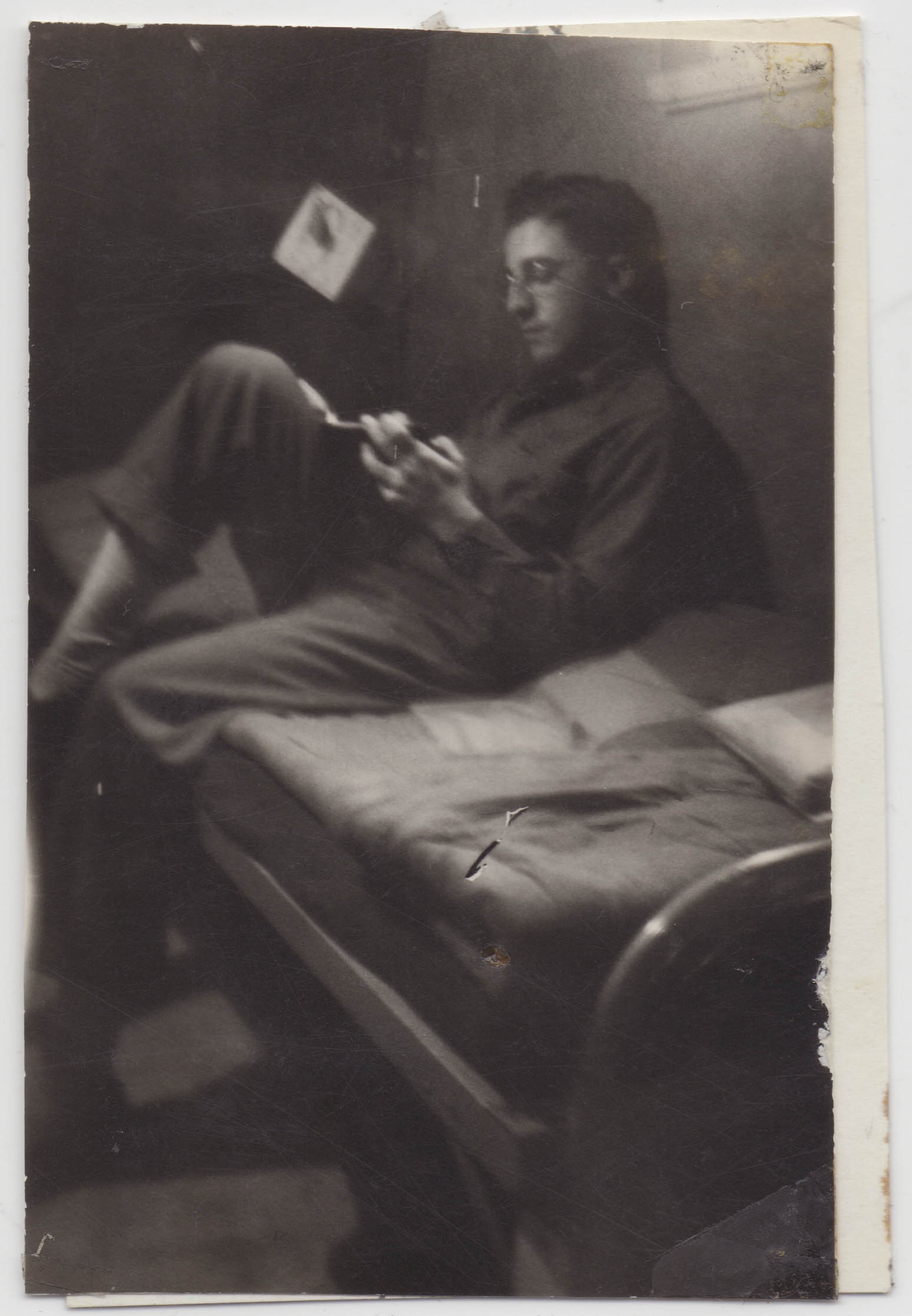 A man writes on a bunk in a dim space