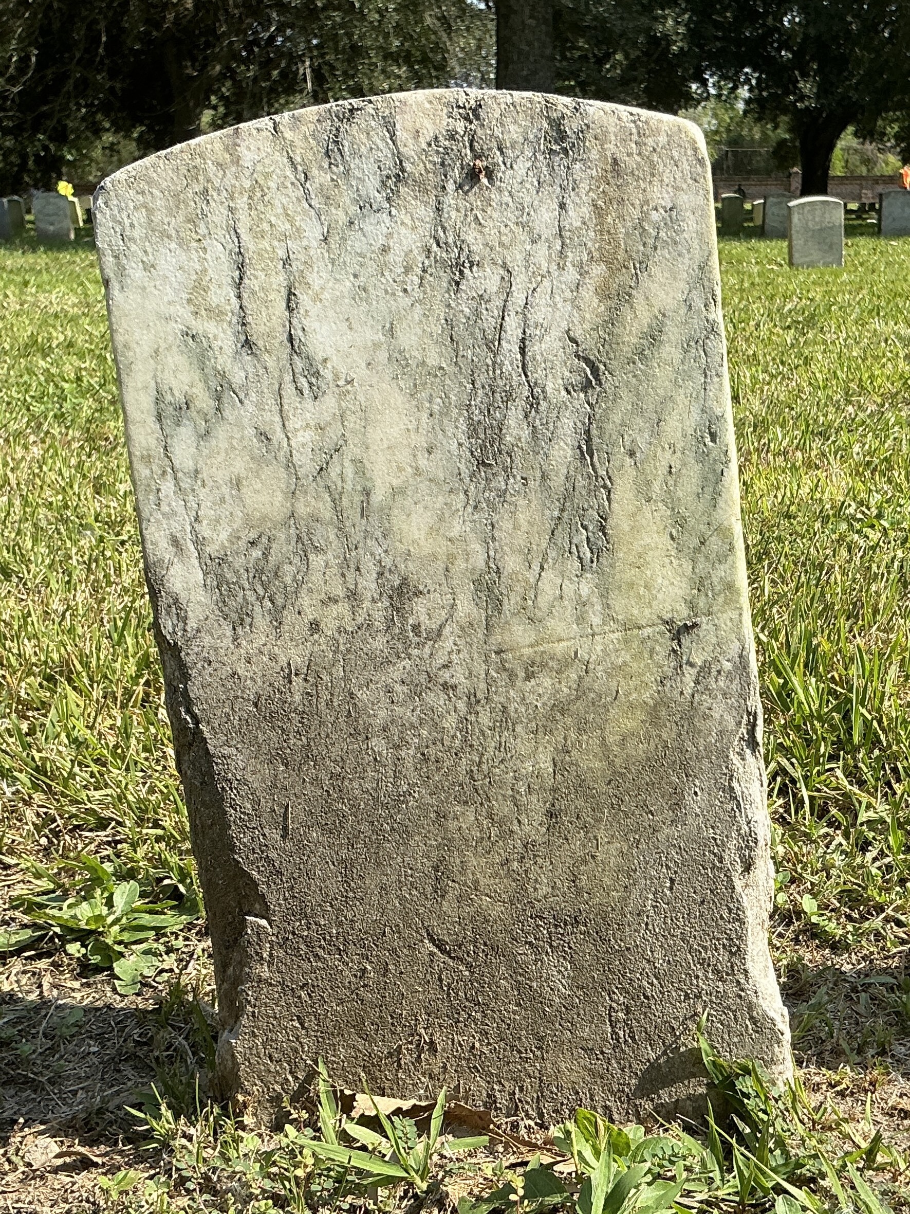 Back of historic upright marble headstone with recessed shield face.