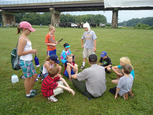 Youth and Park Ranger seated in a field outdoors in Williamsport.