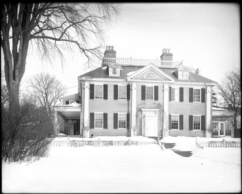 Black and white photo, Georgian mansion with front lawn covered in snow.