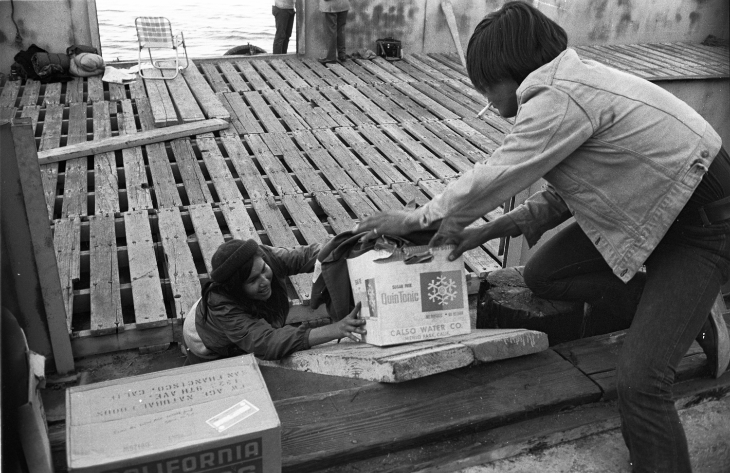 Two men load boxes of supplies on a dock
