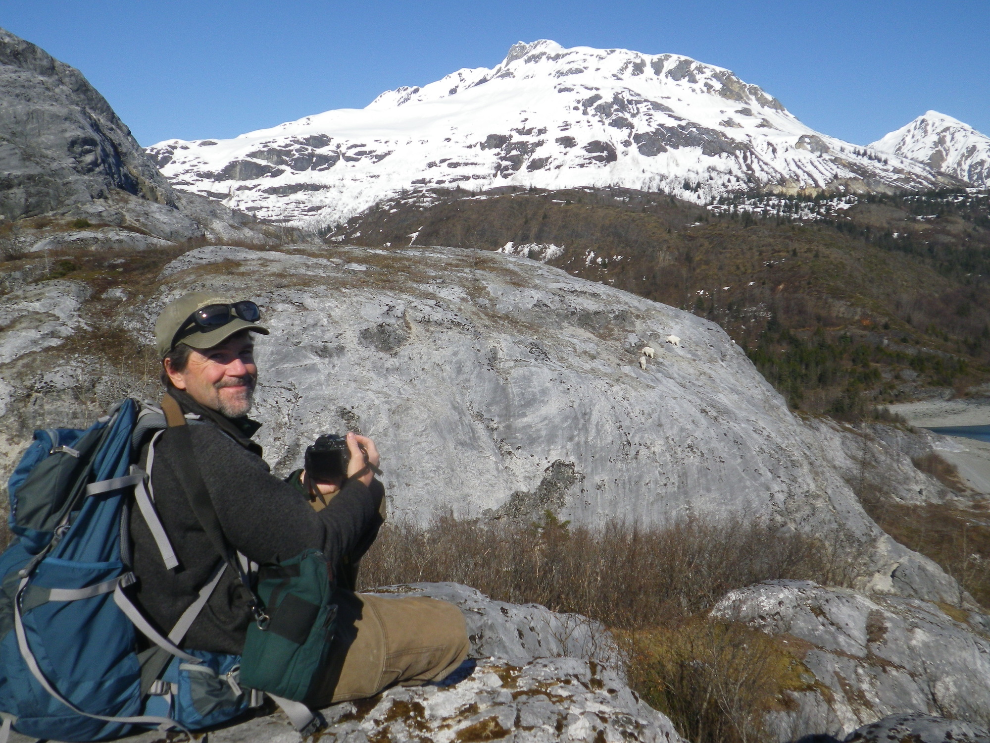A researcher in Glacier Bay watches wildlife climbing up a rocky slope.