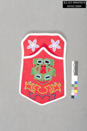 color photo of red pocket with green beaded frog design in the top left and right corners there are white beaded flowers