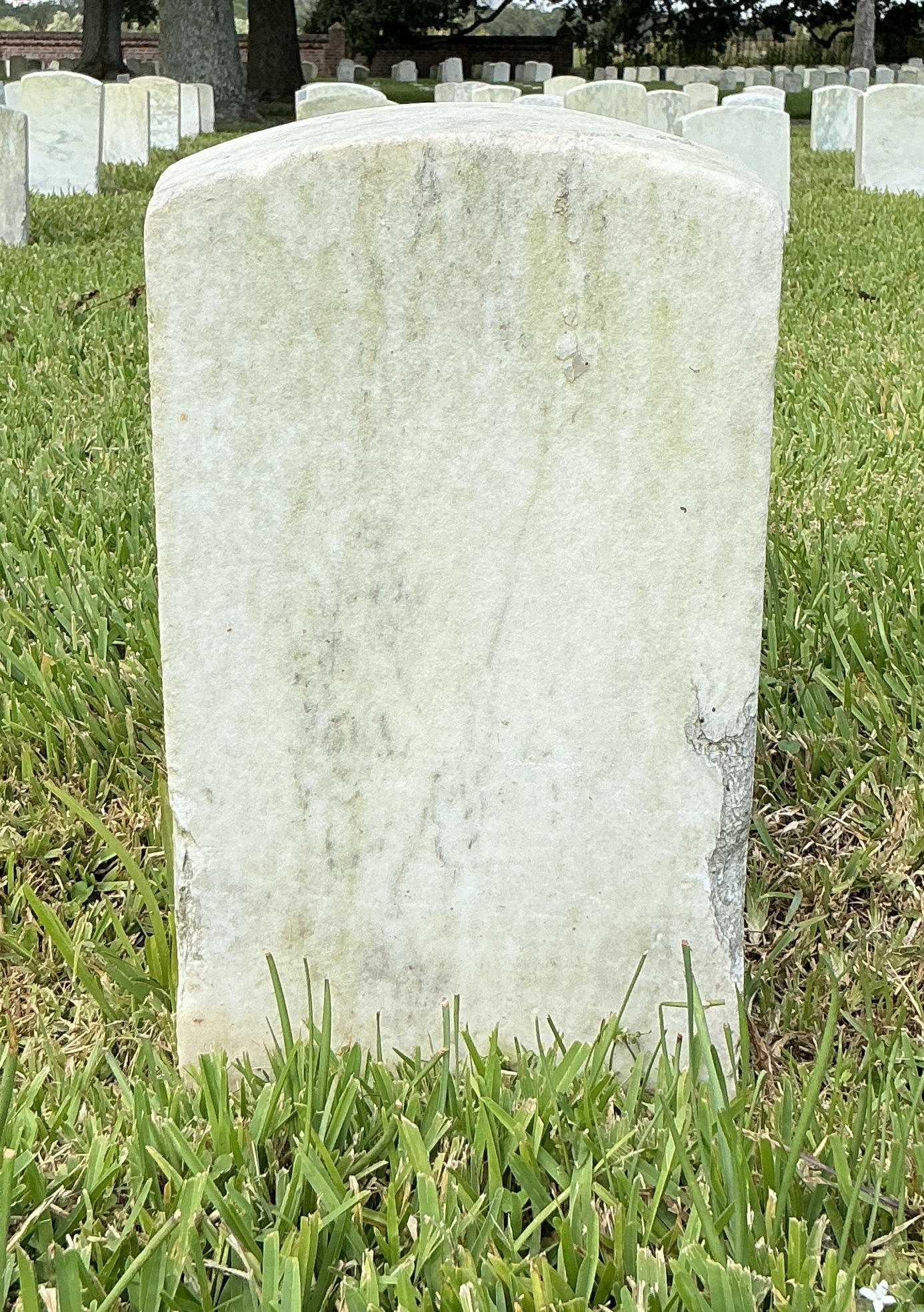 Back of historic upright marble headstone with recessed shield face.