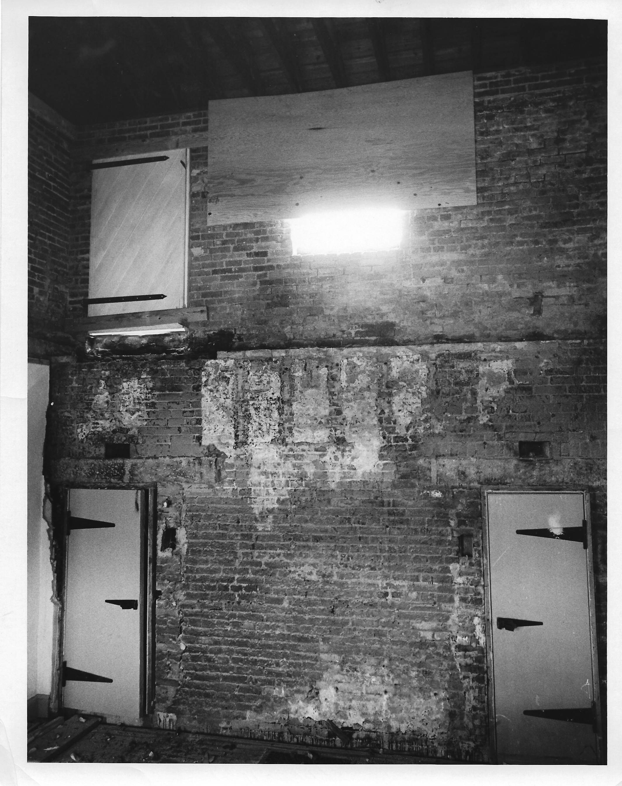 The floor is missing.  The lower floor shows two doors which are the jail cells.  the doors appear to be new.  The top floor has one door on the left, it is closed with a board across it so it does not open.  There is a window that  is about three fourths covered  by plywood.  