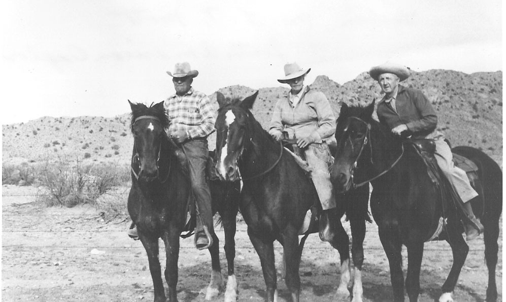 Two men and a woman on dark colored horses. 