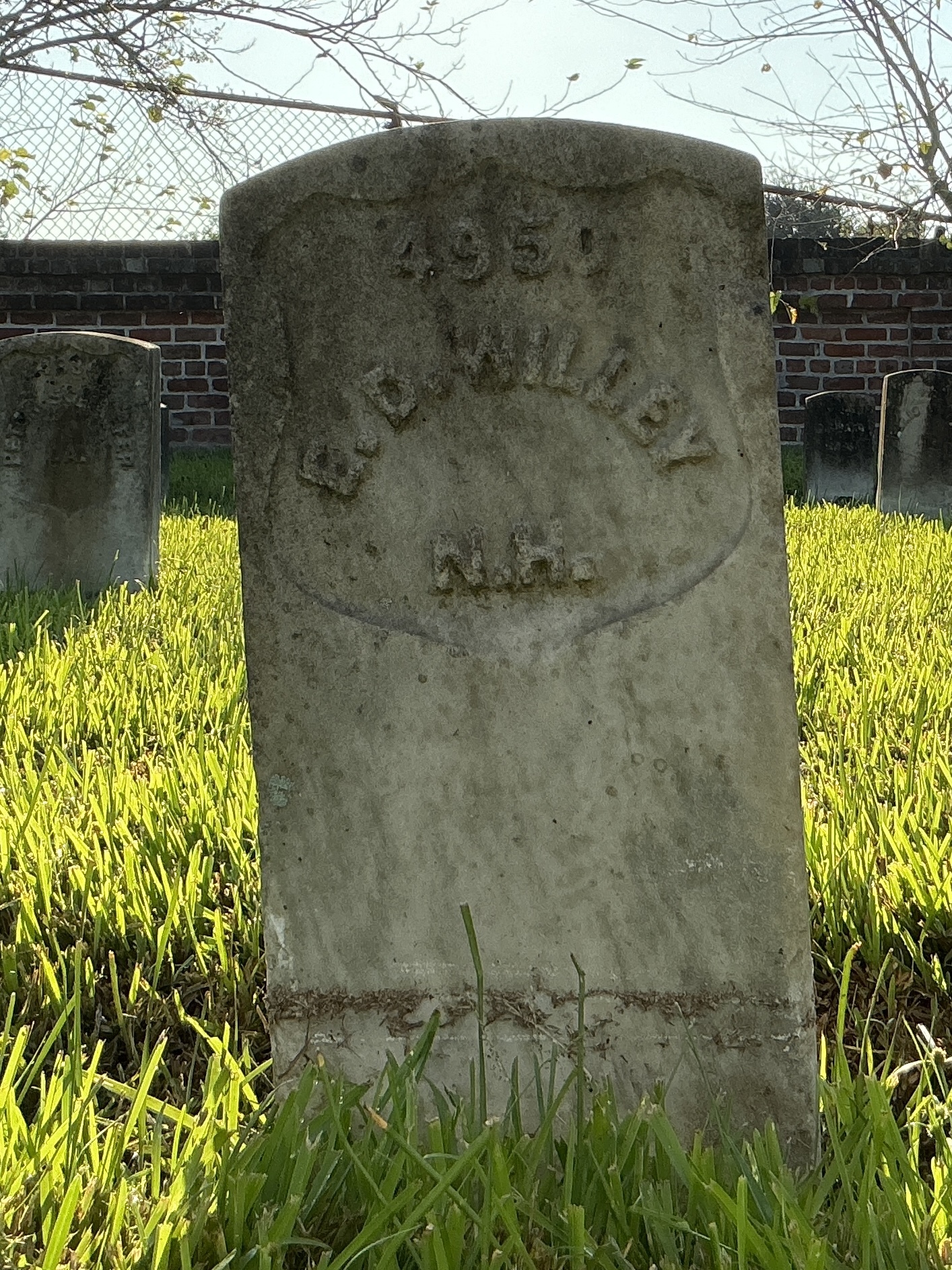 Front of historic upright marble headstone with recessed shield face.